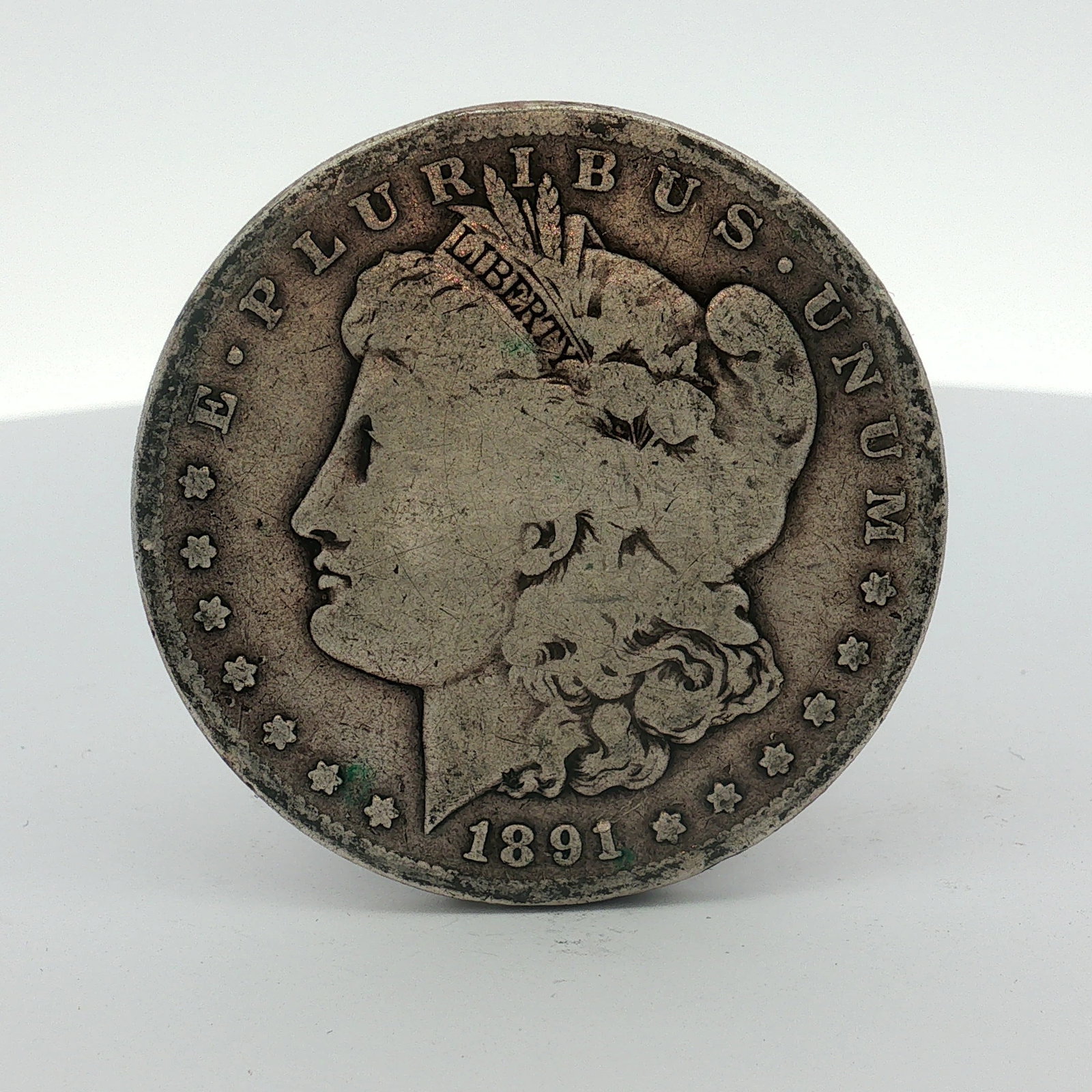 1891-S US One Dollar Morgan Silver Dollar, Circulated: This US 1891-S Morgan dollar is a silver circulating-issue coin struck at the San Francisco Mint. The obverse features the Liberty Head design, and the reverse displays the heraldic eagle within a wre