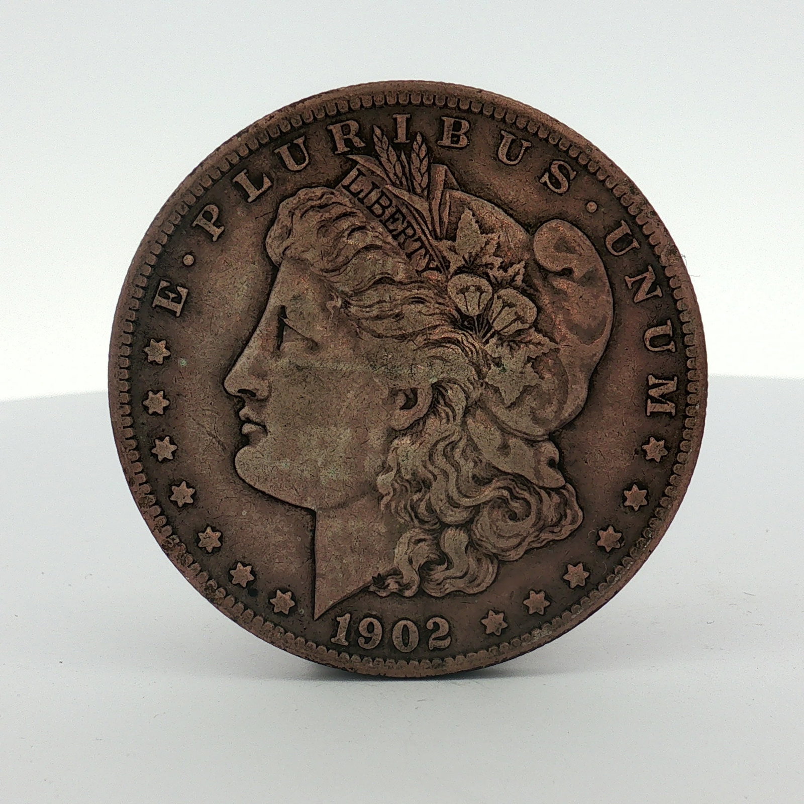 1902-S US One Dollar Morgan Silver Dollar, Circulated: This US Morgan dollar is dated 1902 and bears an S mint mark for the San Francisco Mint. The coin is struck with the Morgan design and features a reeded edge. The piece exhibits an atypical dark, brow