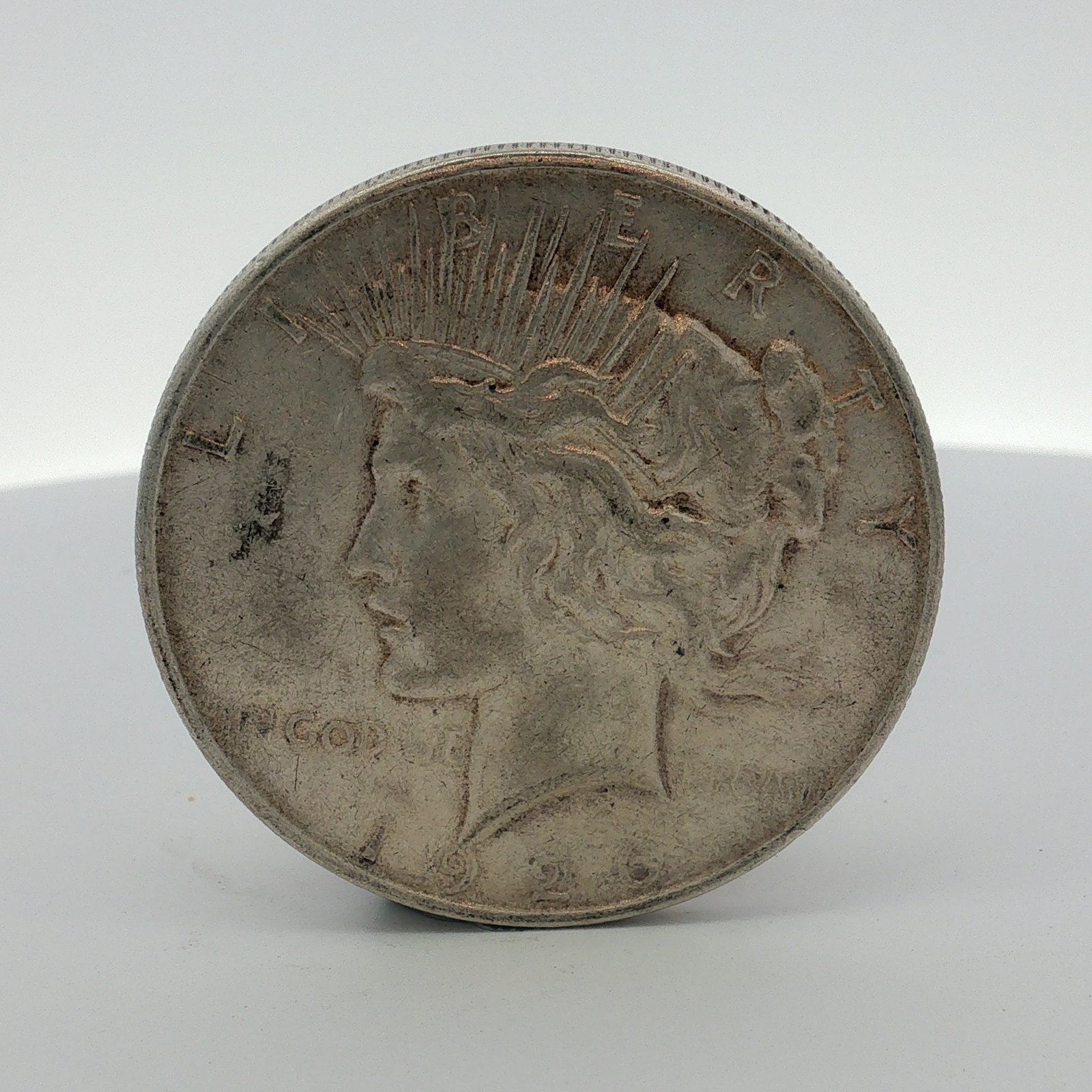 1926-D US One Dollar Peace Silver Dollar, Circulated: This US 1922 Peace dollar was struck at the Denver Mint in 0.900 fine silver, cataloged. The coin features a reeded edge and the standard Peace dollar obverse and reverse designs. Obverse inscriptions