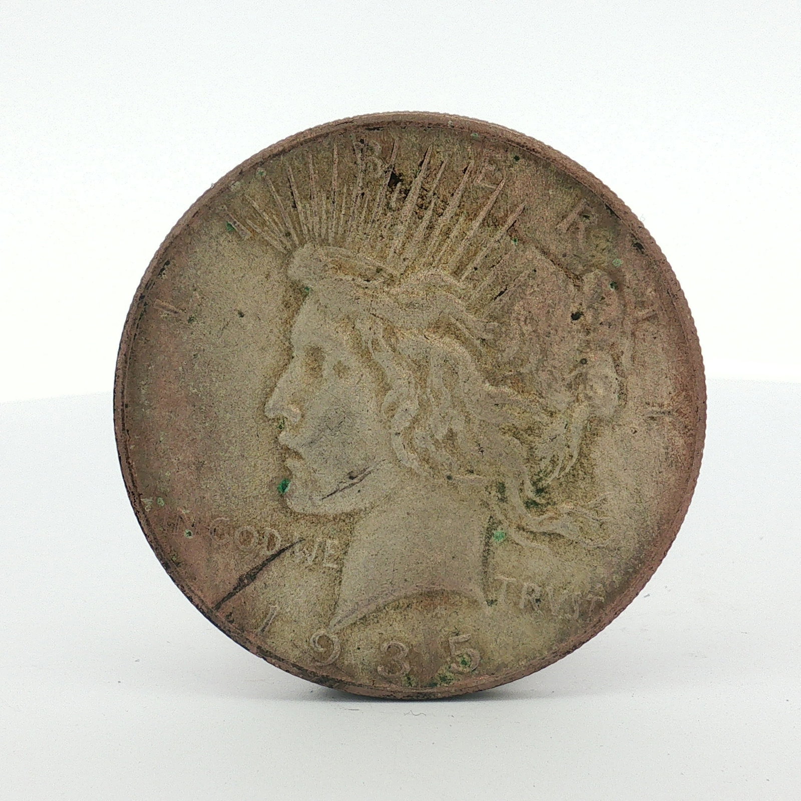 1935 US Peace Silver Dollar: The coin is composed of 90% silver and 10% copper. The obverse features the Liberty head design and the reverse features the eagle on rock design. Inscriptions include LIBERTY, IN GOD WE TRUST, and th