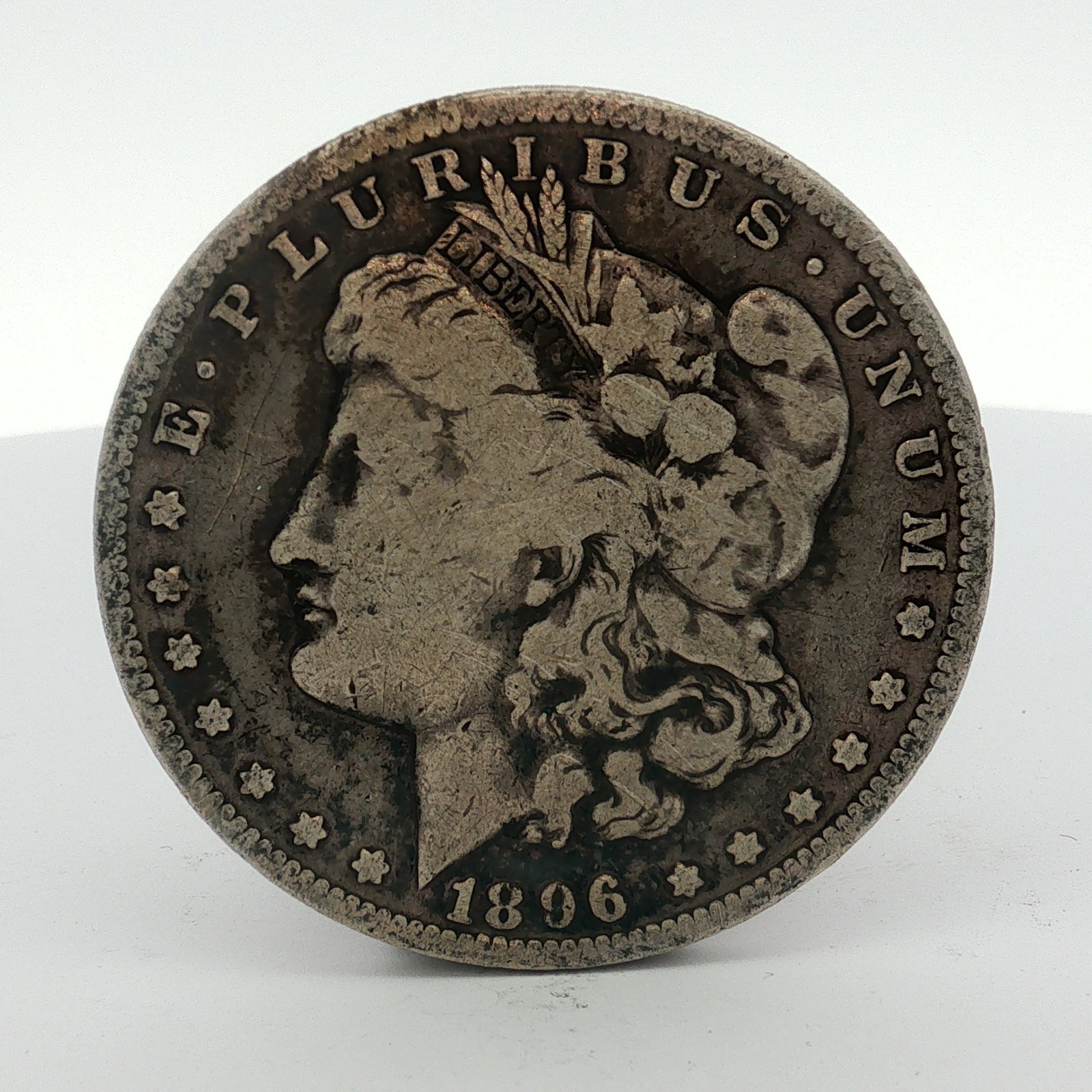 US 1896-O Morgan Silver Dollar: This US Morgan silver dollar is a struck coin dated 1896. It was produced at the New Orleans Mint, as indicated by the O mint mark. The piece is composed of 90 percent silver and 10 percent copper. Th