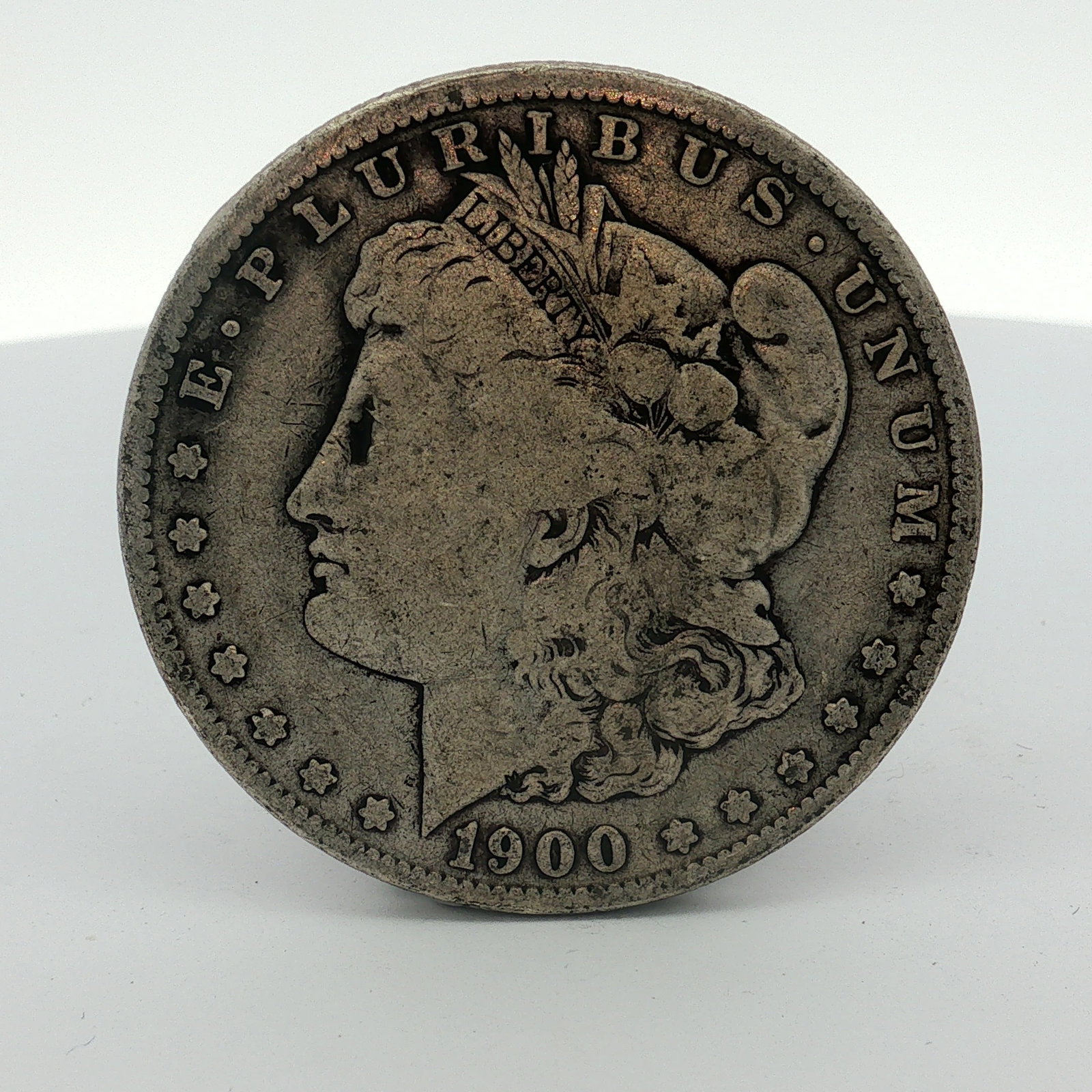 US 1900-O Morgan Silver Dollar: This coin features the Liberty Head obverse and the Eagle with wreath reverse. Obverse inscriptions include E PLURIBUS UNUM and the date 1900. Reverse inscriptions include UNITED STATES OF AMERICA, th