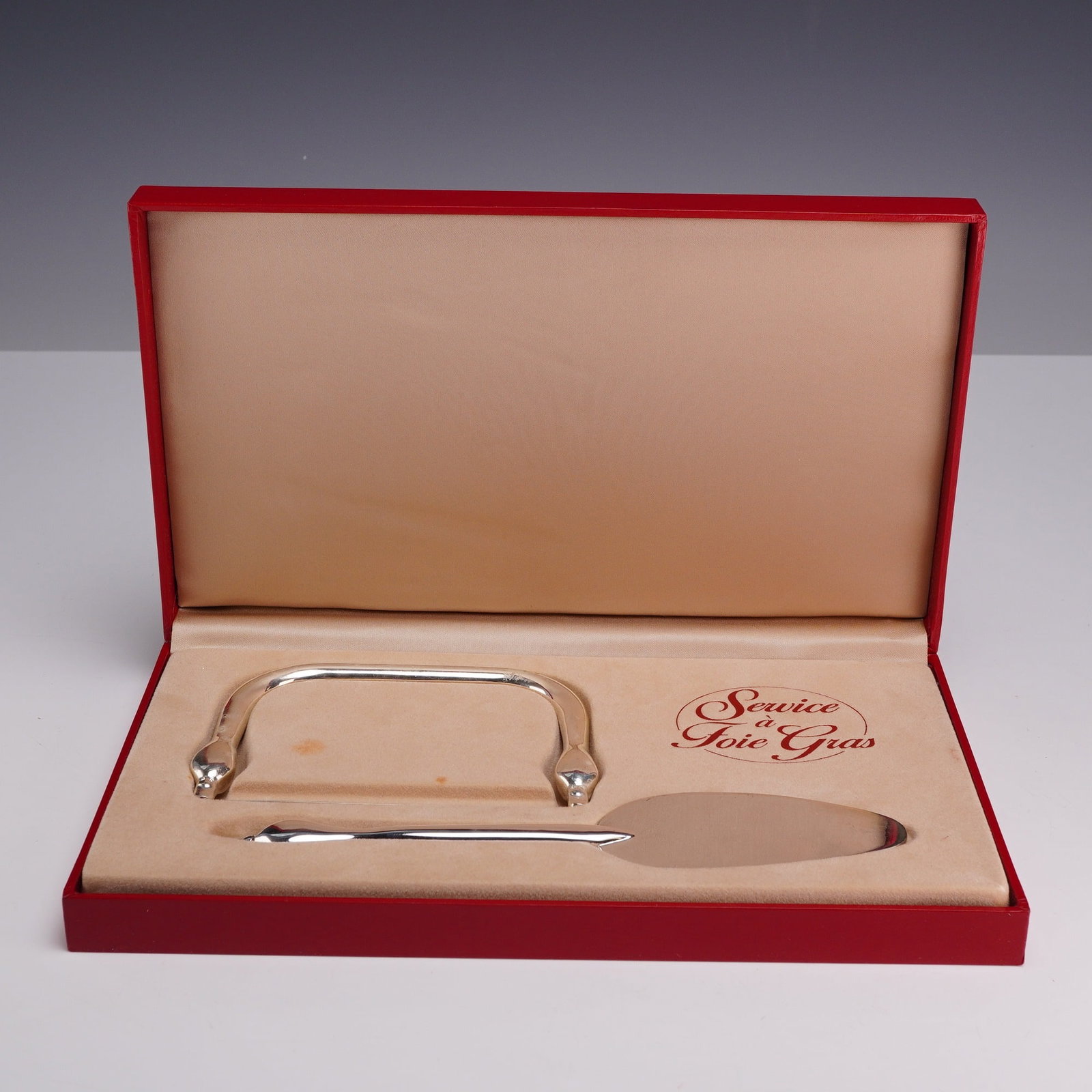 Two-Piece Silver-Plated Foie Gras Serving Set with Figural Bird Finials: A two-piece service a foie gras in box, consisting of a lyre-style foie gras cutter and a matching serving spatula. The pieces are constructed from silver-plated metal, each featuring a figural finial
