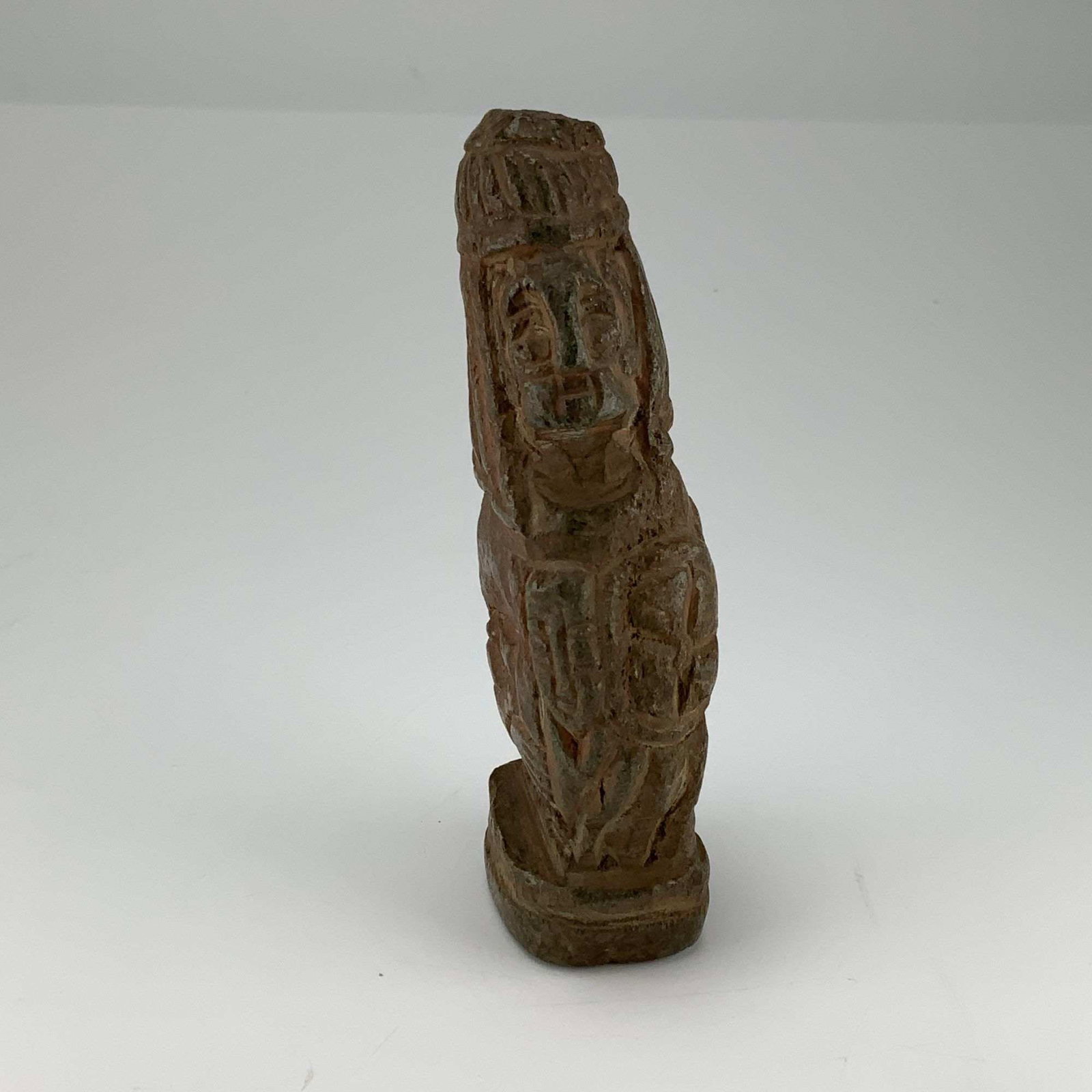 Carved Reddish Brown Stone Seal Handle with Mayan Statue of a God: This object is a carved stone seal handle of tapered cylindrical form, crafted from a dense reddish brown stone. The exterior features complex relief carvings and incised decorations. One side depicts