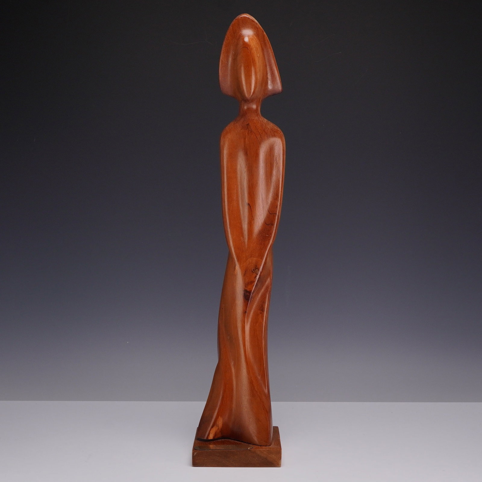 Miguel Estrella, Adolescente, Carved Mahogany Sculpture, 1991: This modernist sculpture, titled Adolescente, was carved by Miguel Estrella in 1991. The work is crafted from mahogany (caoba) and depicts a stylized, elongated female figure with fluid, abstract line