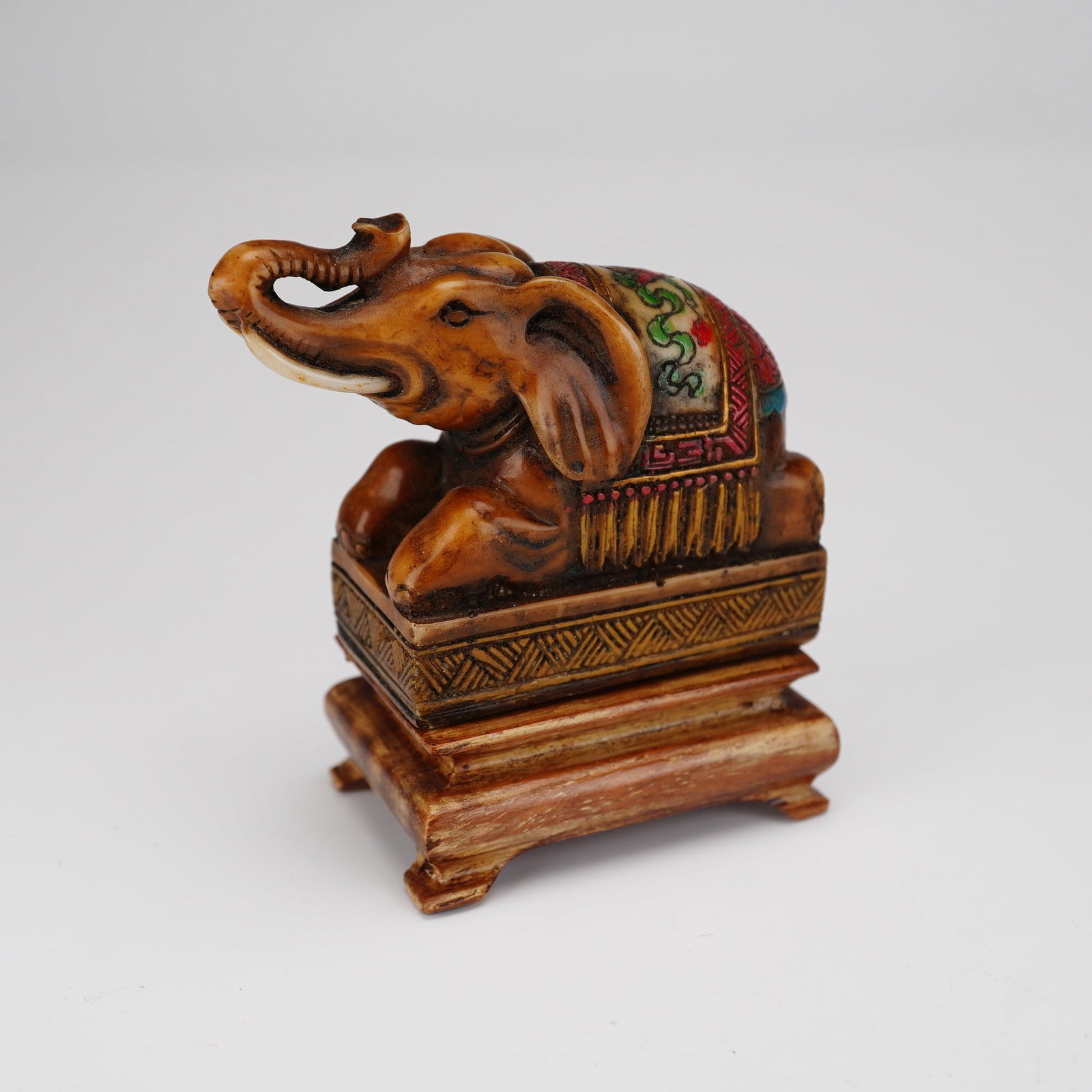 Hand-Carved Stone Elephant Figural Seal with Wood Stand: This lot features a hand-carved stone elephant figurine serving as a seal, accompanied by a separate wooden display stand. The elephant is depicted in a recumbent position with its trunk raised in an 