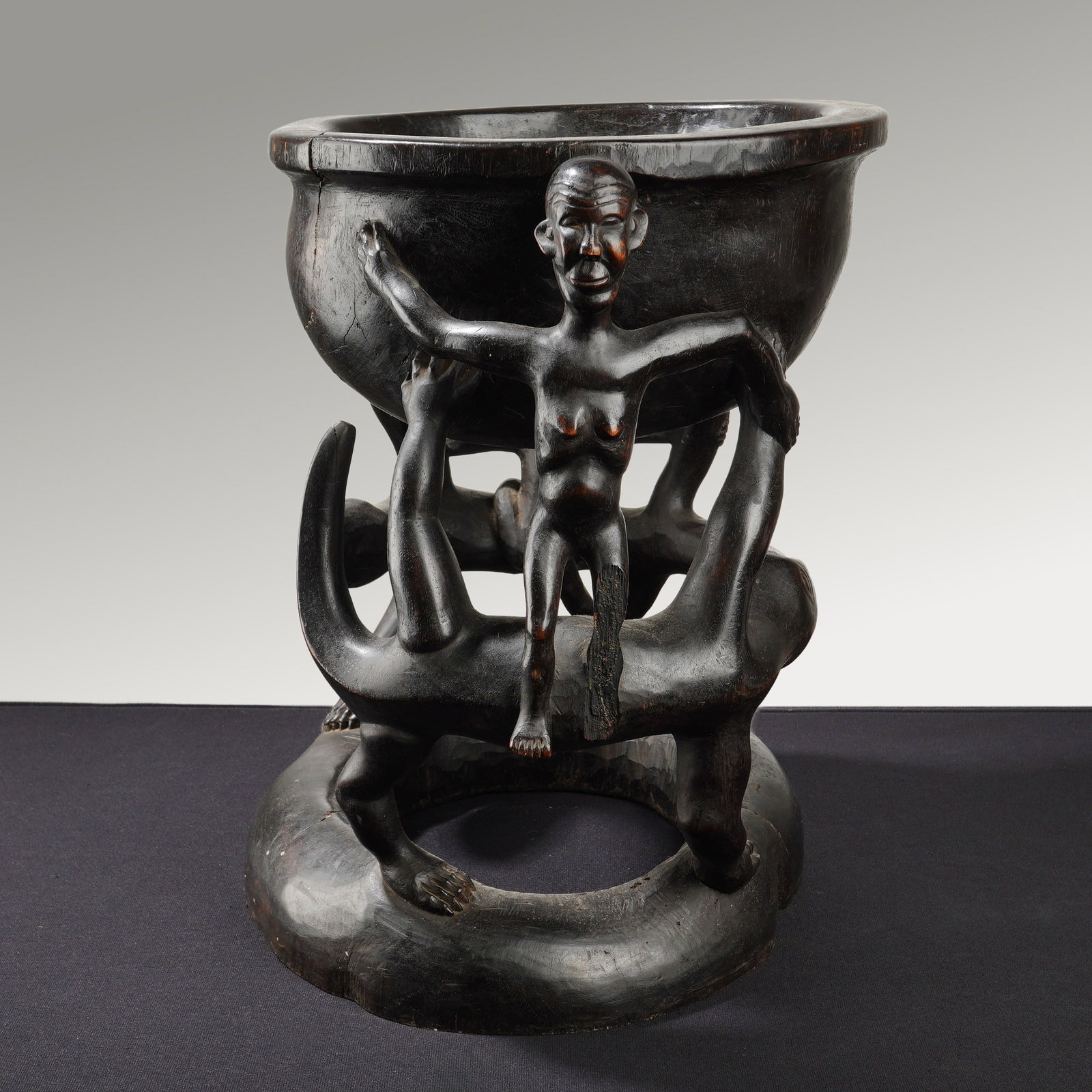 4pc African Tribal Wooden Bowl and Serving Spoons: This lot features a large hand-carved wooden figural bowl. The primary piece is carved from a single block of dark, polished wood and features an intricate openwork pedestal. The base decoration inclu