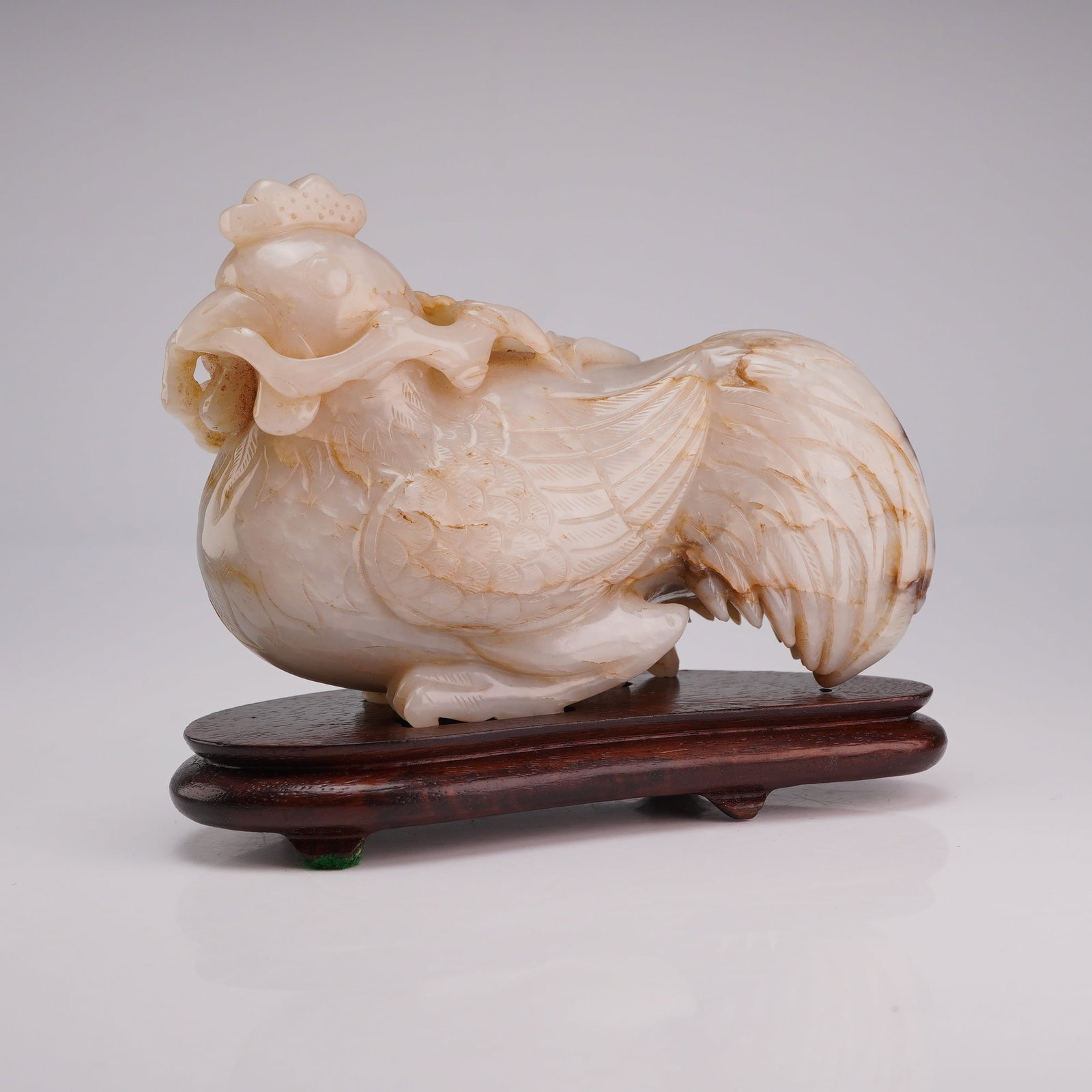 Nephrite Jade Carving of Rooster with Lingzhi, Wood Stand: A carved nephrite jade figure of a rooster with Lingzhi mushroom, accompanied by a wooden stand. Dimensions 4.5"L x 1.5"W x 3.5"H Weight 15.0 oz