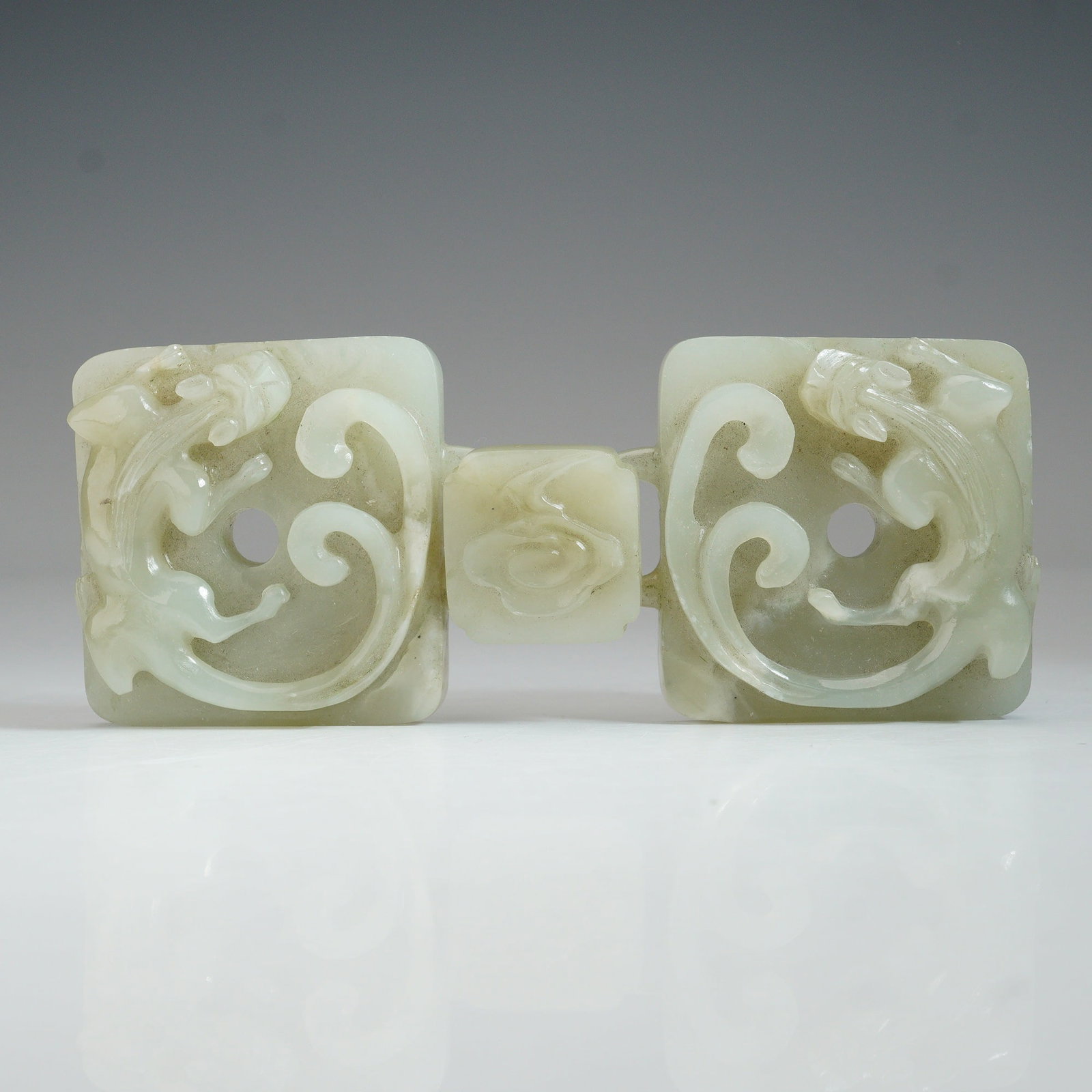 Chinese Chilong Celadon Nephrite Jade Buckle: Composed of three interconnected pieces, intricately carved with openwork designs featuring stylized chilong motifs in dynamic, coiled positions. The two square plaques are pierced with central circul