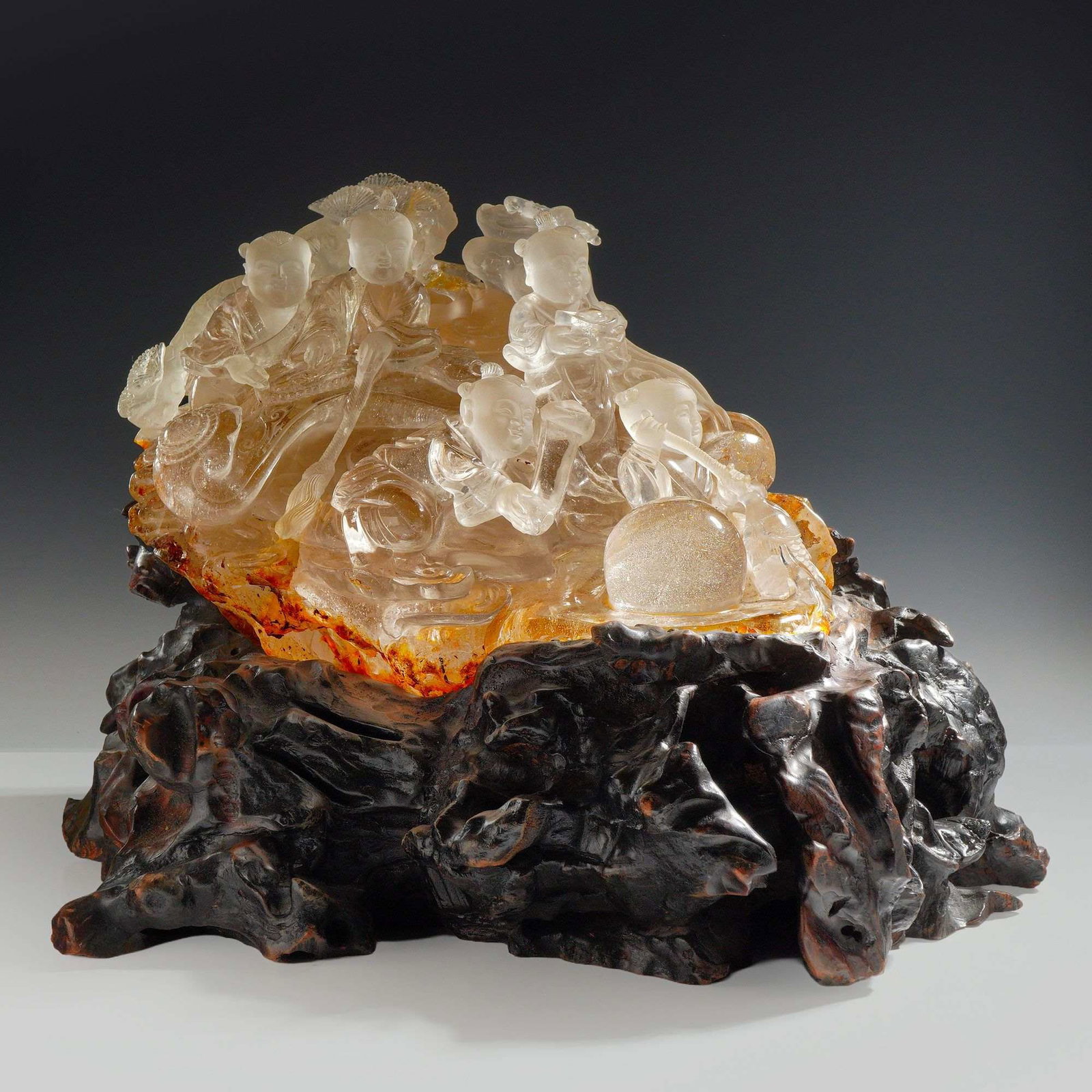 Chinese Large Natural Carved Quartz Crystal Sculpture: This Chinese figural carving is masterfully crafted from a single piece of clear and frosted rock crystal quartz. The composition depicts several boys in traditional attire, each holding auspicious sy