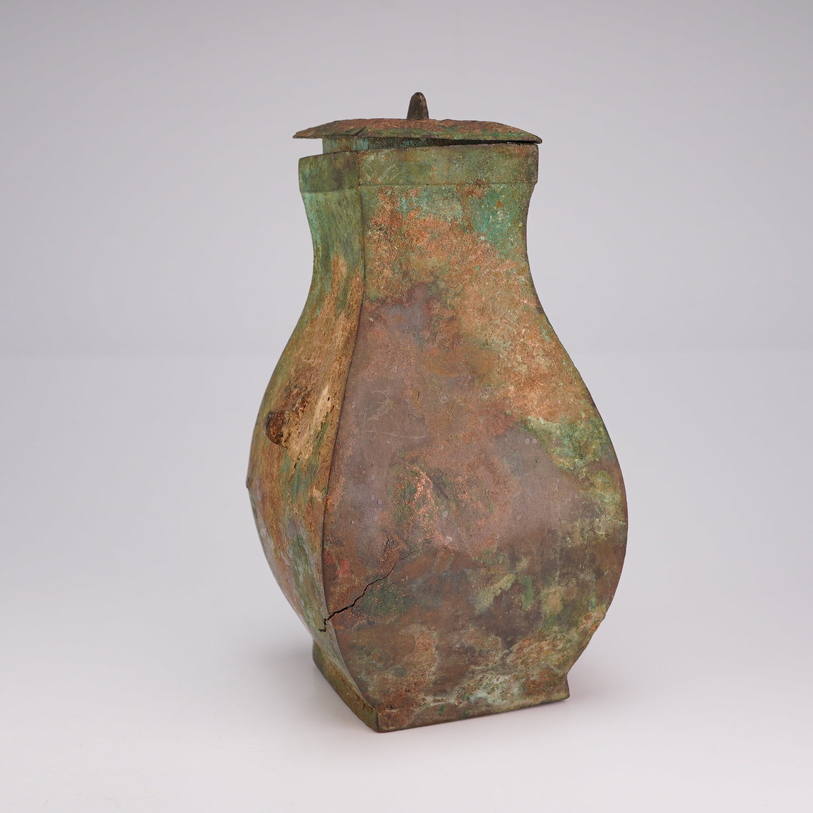 Chinese Archaic Bronze Hu-Form Vase, Han Dynasty with Cover: An archaic Chinese Hu-shaped bronze vase with a lid featuring a faint geometric pattern. Dimensions 2.5"L x 2.5"W x 5"H Weight 8.0 oz