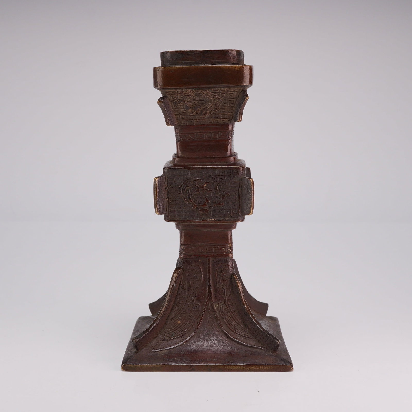 Chinese Archaic Style Bronze Gu Vase: A small Chinese bronze vase in archaic style, Gu-shaped, featuring a flared square mouth and a relief key pattern. Dimensions 2.75"L x 2.75"W x 6"H Weight 1.10 lb