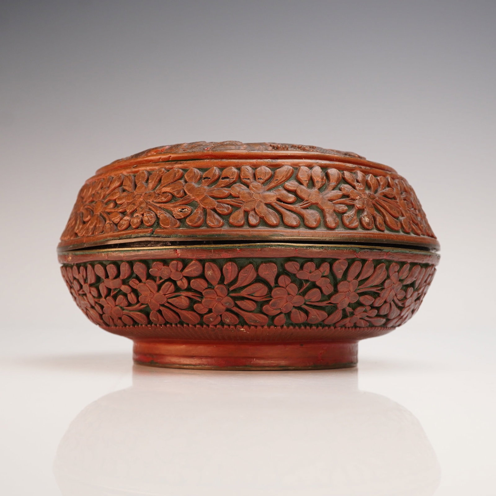 Chinese Carved Cinnabar Round Box with Landscape Scene: A Chinese carved cinnabar round box, dating approximately to the late 19th to early 20th century. The domed cover is richly worked with a dynamic landscape scene featuring figures, animals, and pavili