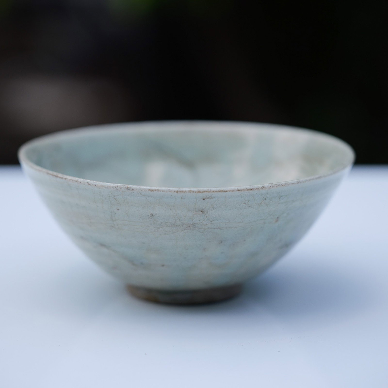 Chinese Celadon Ware Bowl: This antique Chinese celadon ware bowl features a pale gray-toned glaze. The exterior of the bowl is undecorated, yet displays a series of horizontal concentric lines resulting from the potter's wheel