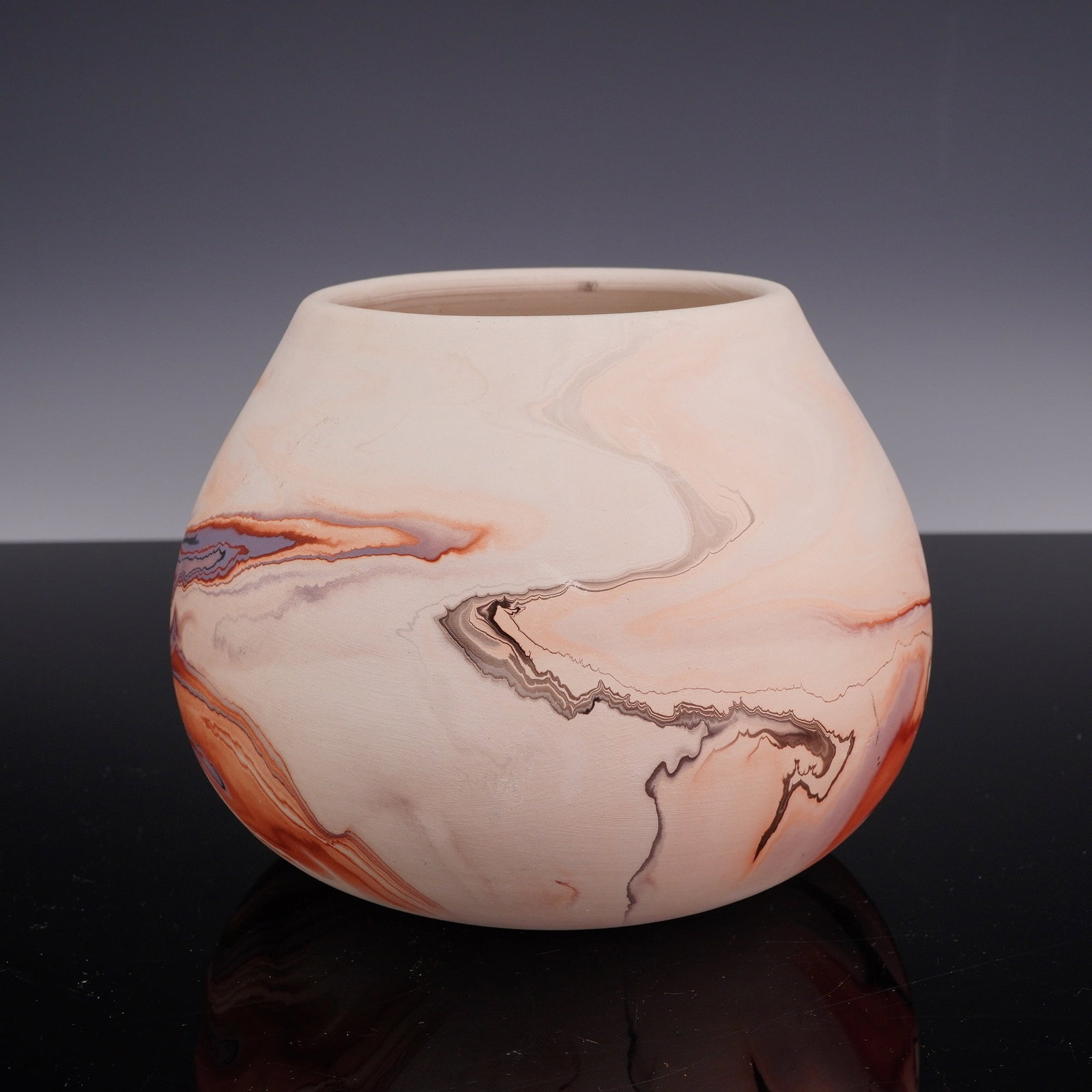 Nemadji Indian River Pottery Marbled Art Vase: A Nemadji Indian River Pottery art vase featuring a bulbous, globular form with a wide, slightly tapered mouth. The piece is constructed of earthenware with a matte, unglazed bisque finish. The exteri