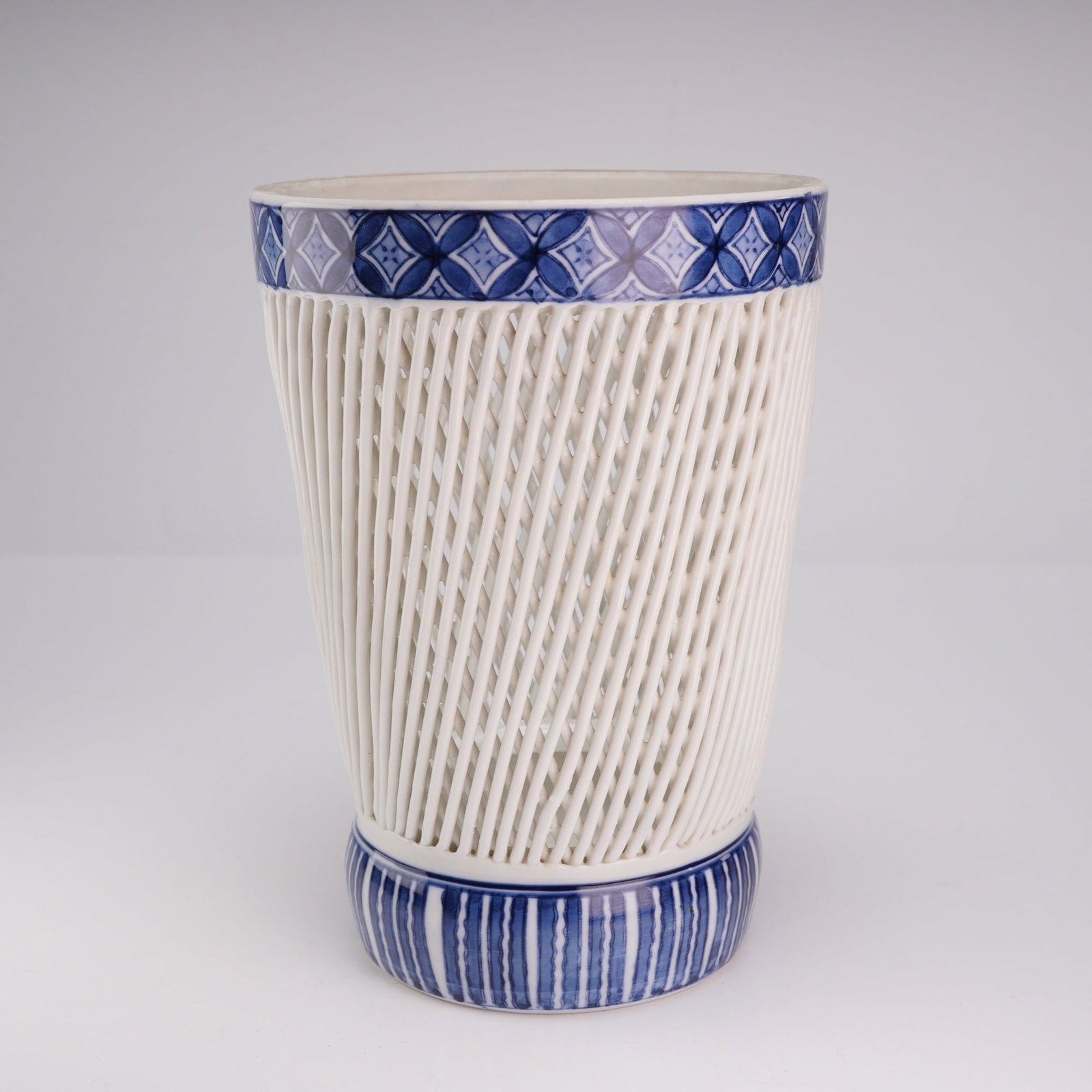 Japanese Blue and White Porcelain Hirado Woven Vase: A Japanese blue and white Hirado ware porcelain vase featuring a woven body design, with geometric blue-glaze borders near the rim and base. The underside is marked with blue Japanese characters. Dime
