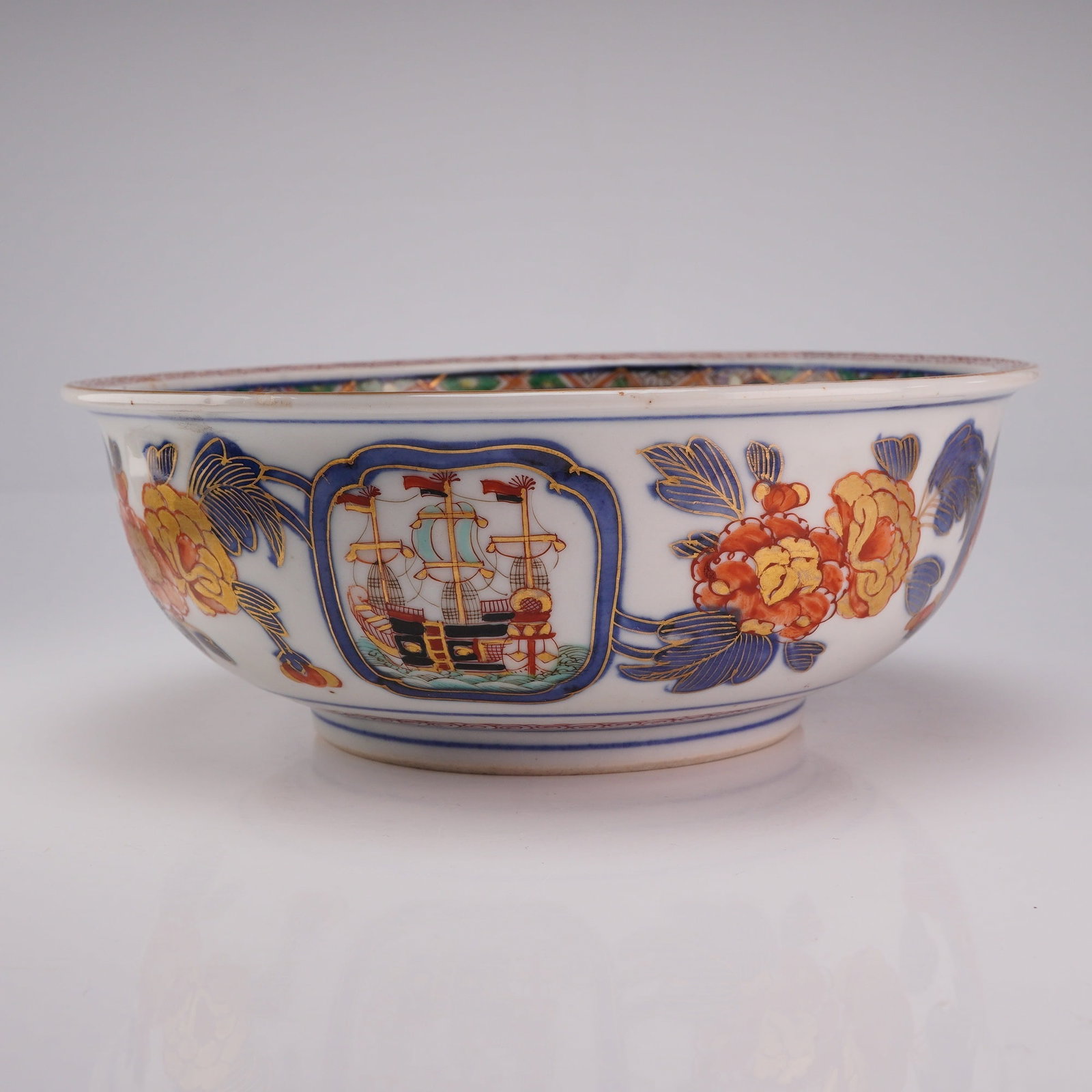 Japanese Imari Blackship and Nanban Bowl, Character on Foot: A ceramic Japanese Imari bowl hand-painted with Black Ship, Nanban, and floral motifs, featuring detailed gilding and shades of red, blue, green, and black. The base is marked with a Japanese characte
