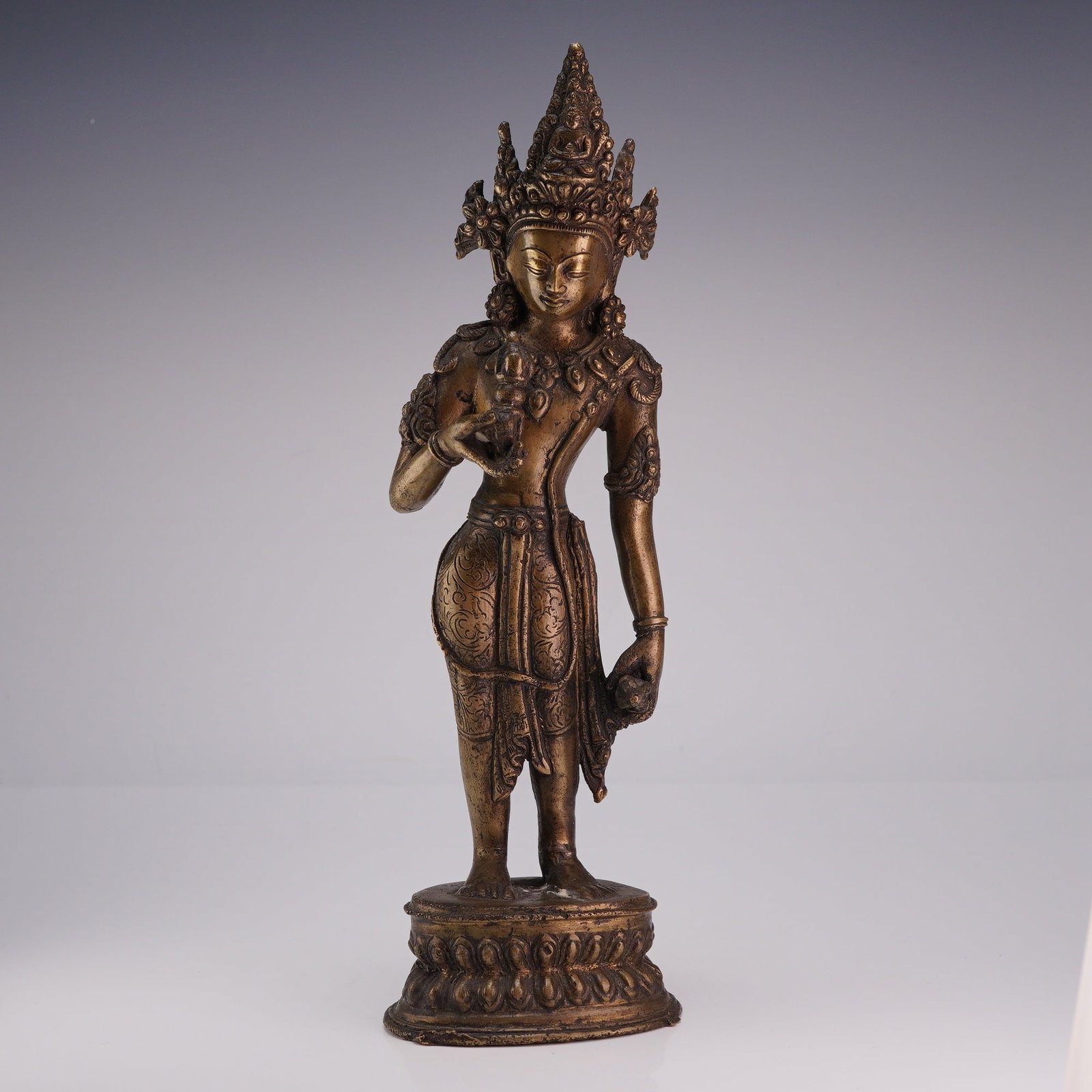 Nepalese Bronze Standing Figure Holding Dorje: Nepalese bronze figurine standing atop an oval-shaped base, holding symbolic objects in each hand. Dimensions 3"L x 2.5"W x 10"H Weight 2.30 lbs