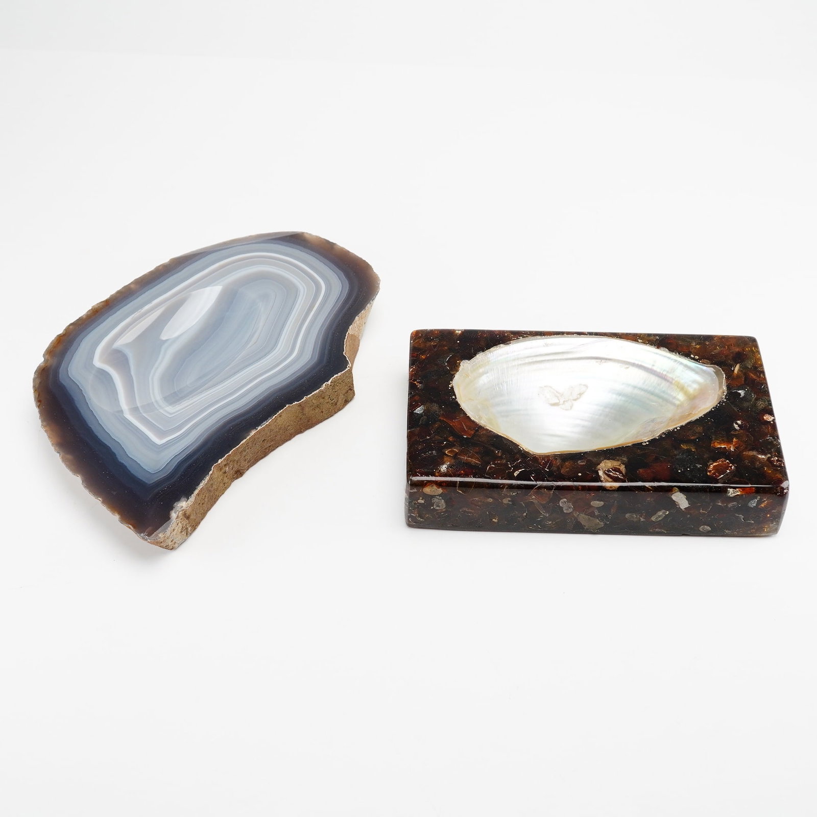 Two Natural Stone and Mother of Pearl Specimen Ashtrays: A group of two decorative specimen objects, functioning as ashtrays or shallow dishes. The first item is a natural agate slice featuring concentric banding in shades of blue, grey, and white. It has