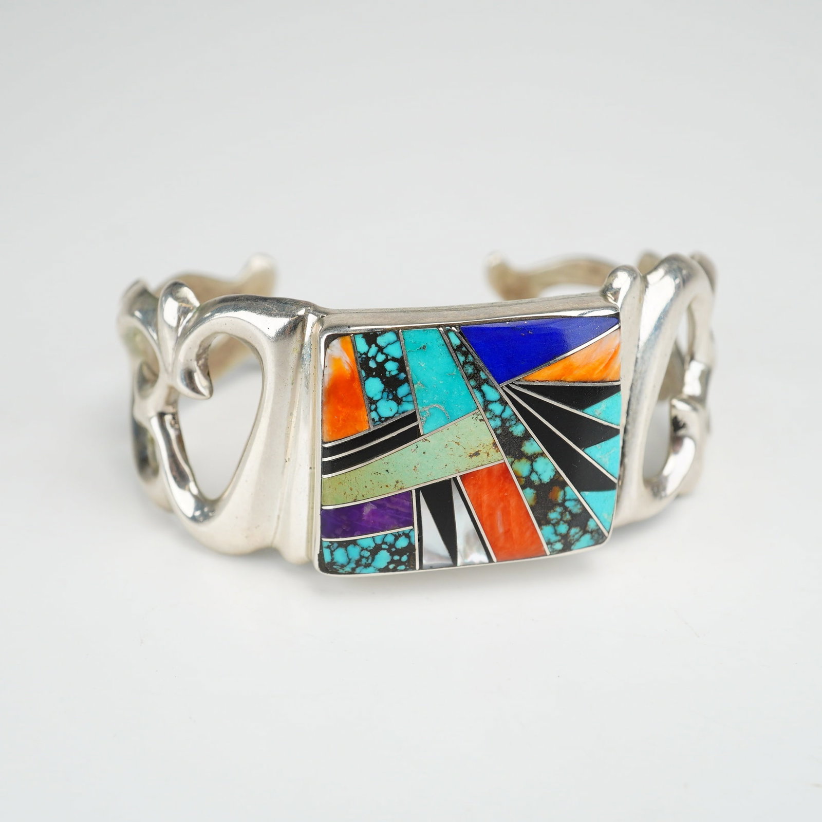 Frank Chee Navajo Sterling Silver and Multi-Stone Inlay Native American Cuff Bracelet: This Native American cuff bracelet is crafted in sterling silver by Navajo jeweler Frank Chee. The piece features a central rectangular plaque decorated with a complex geometric micro-mosaic inlay. Th