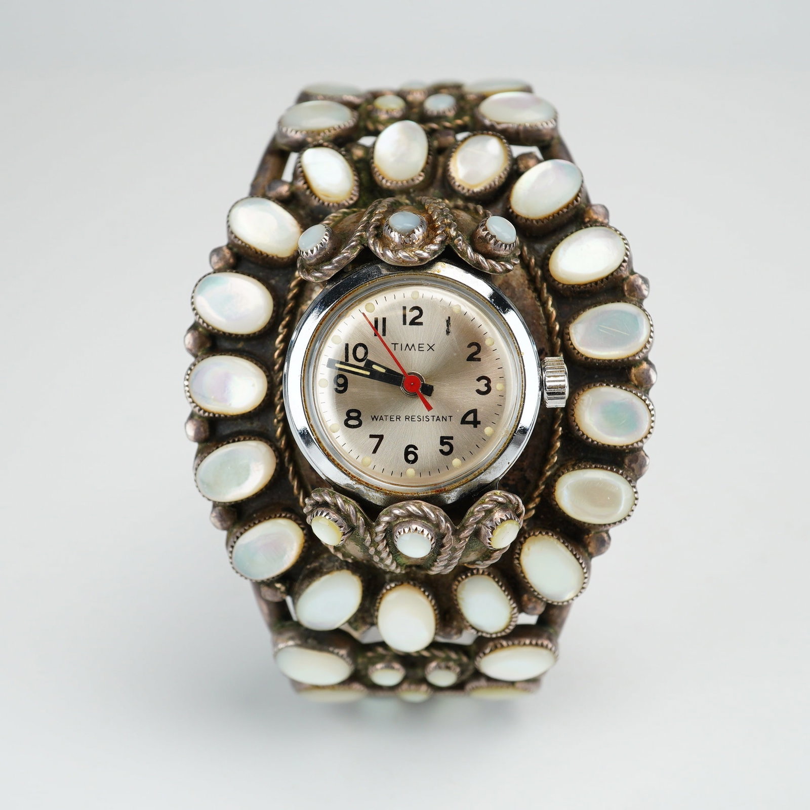 Timex Watch in a Sterling Silver Native American Mother-of-Pearl Cluster Cuff Bracelet: This ladies watch features a Timex watch head integrated into a handcrafted sterling silver Native American cuff bracelet. The watch dial is finished in a silver sunburst tone with black Arabic