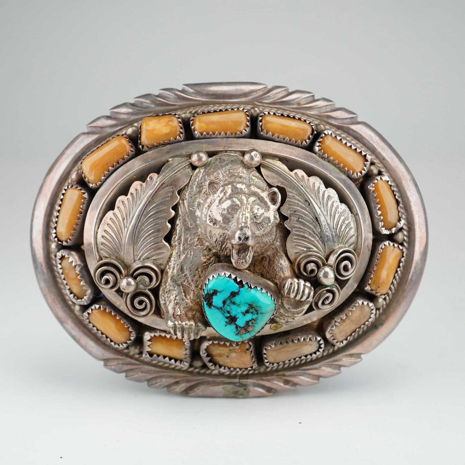 Navajo J.W. Toadlena Sterling Silver Bear Motif Belt Buckle with Turquoise: This Navajo sterling silver belt buckle is the work of silversmith J.W. Toadlena. The oval-shaped buckle features a central cast silver bear figure in relief, accented by a single heart-shaped