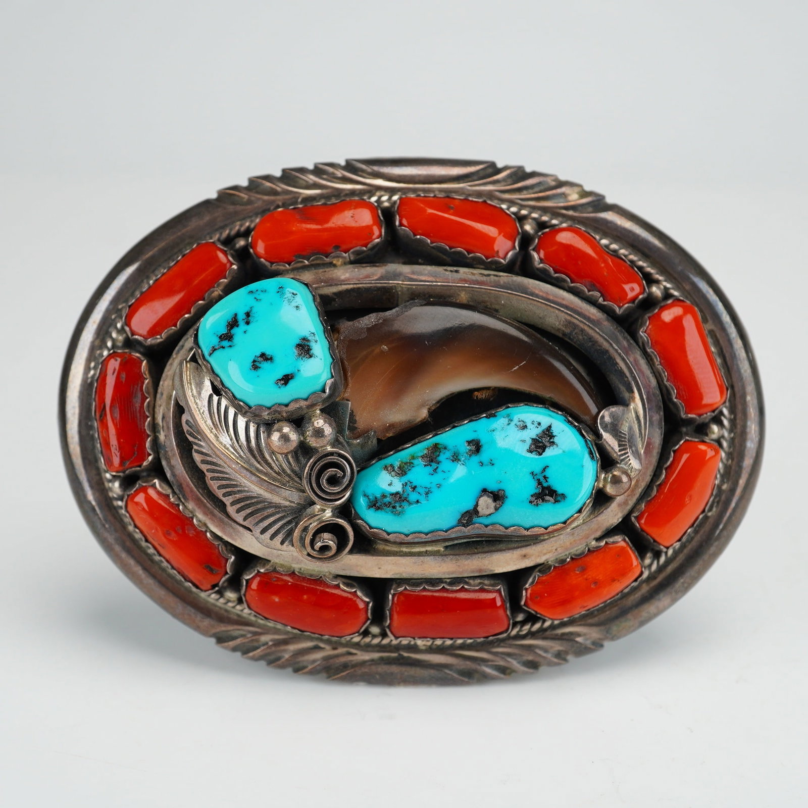Navajo J.W. Toadlena Sterling Silver Turquoise Coral and Bear Claw Belt Buckle: This Navajo sterling silver belt buckle is the work of silversmith J.W. Toadlena. The face of the buckle features a central natural bear claw paired with two turquoise cabochons displaying natural