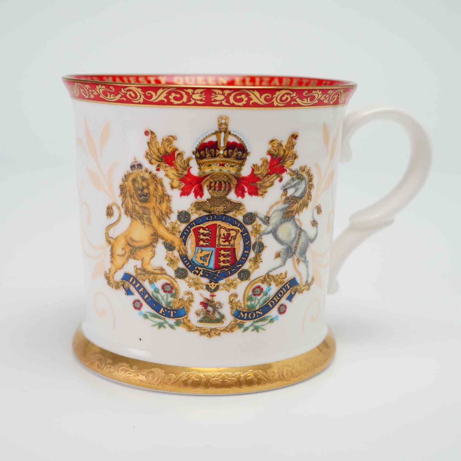 Royal Collection Trust Queen Elizabeth II Commemorative Bone China Cup with Box: A fine bone china commemorative tankard-style mug manufactured by the Royal Collection Trust in England. The vessel features a flared rim and foot with a scrolled handle. The decoration consists of mu