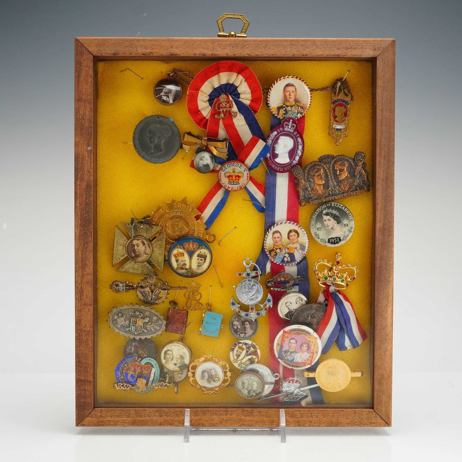 A Collection of British Royal Family Commemorative Pins and Medals: A collection of English royalty pins, medals, and badges commemorating the British Monarchy from the late 19th century to the mid-20th century. The assortment includes items celebrating the reigns and