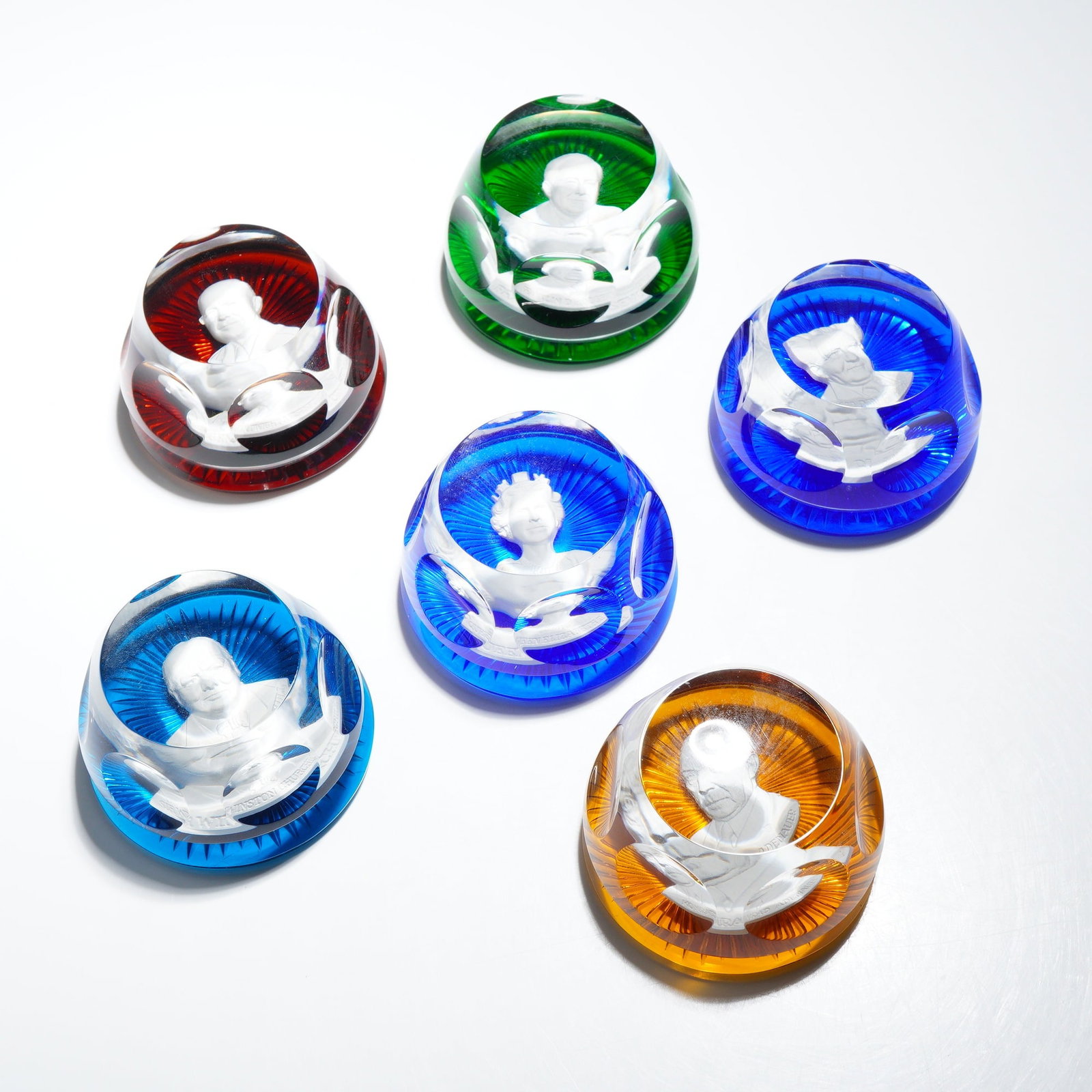 6pc Baccarat Franklin Mint Crystal Cameo Paperweights: A set of six faceted glass sulfide paperweights produced by Baccarat for The Franklin Mint. Each piece features a white sulfide cameo inclusion of a historical figure. The set includes portraits of Si
