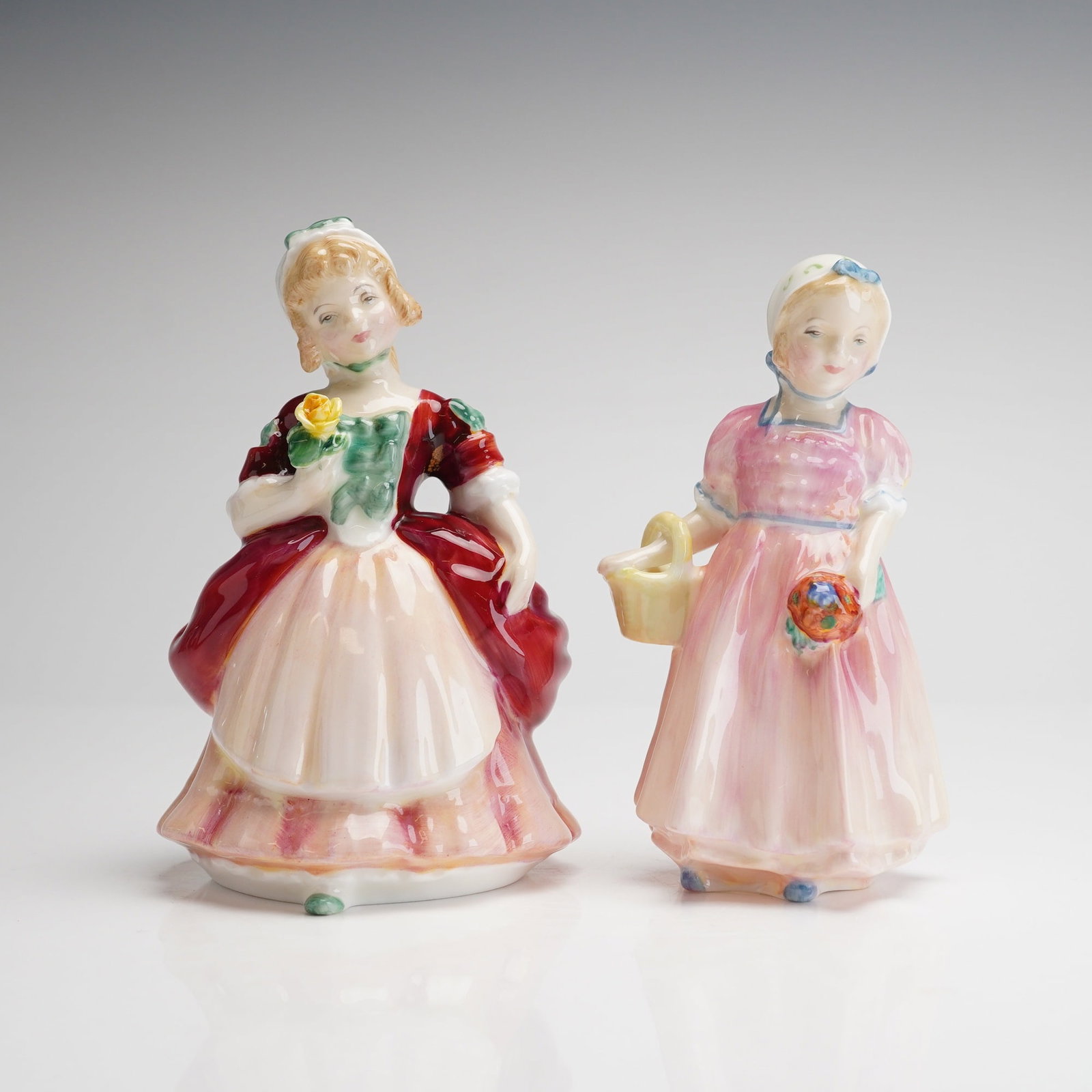 2pc Royal Doulton Figurines Valerie and Tinkie Bell: The collection includes Valerie, HN 2107, and Tinkie Bell, HN 1677. Both pieces depict young women in stylized period attire. The figurine Valerie, copyrighted 1952, is dressed in deep red and pale pi