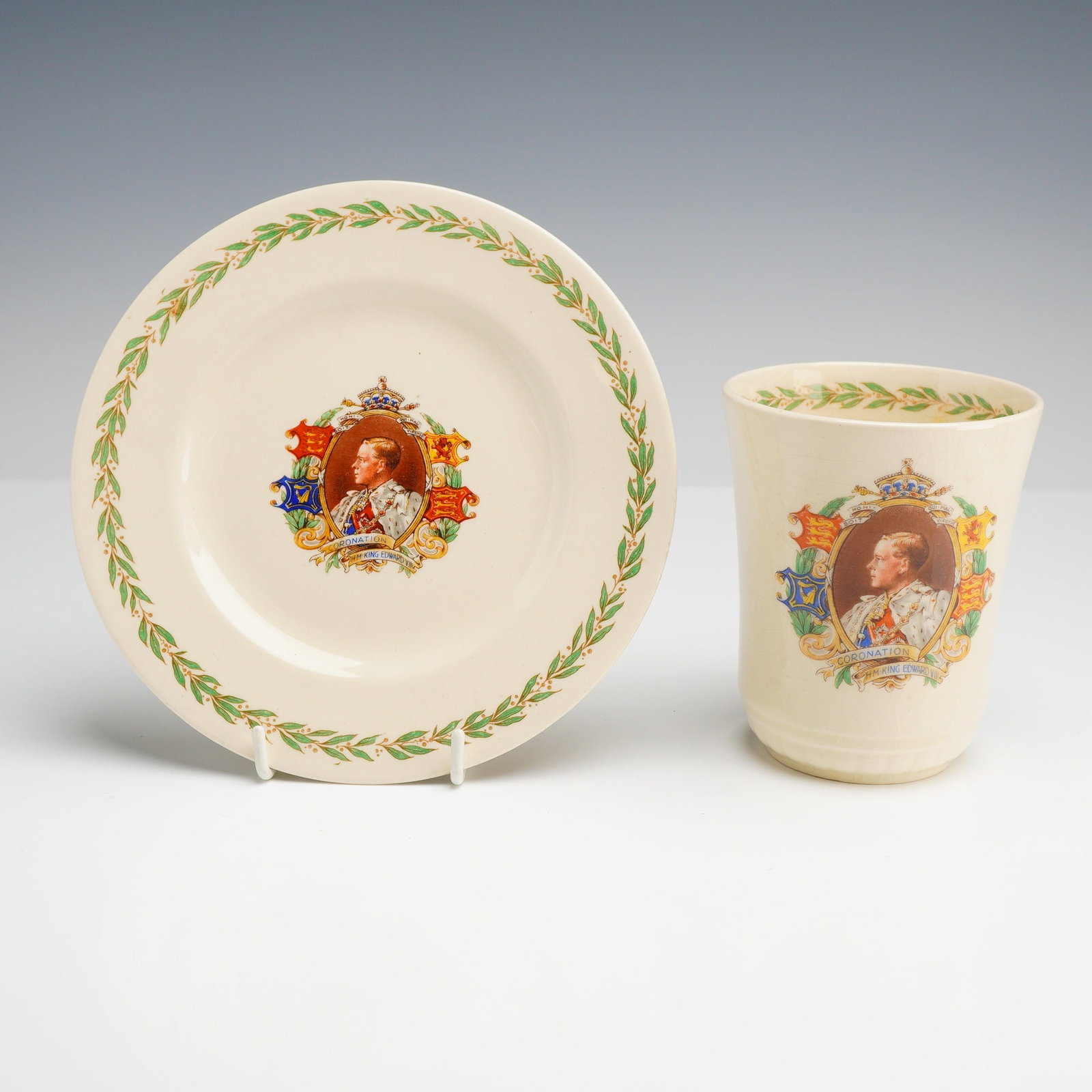 2pc Royal Doulton King Edward VIII 1937 Coronation Commemorative Ceramics: This grouping of commemorative ceramics was manufactured by Royal Doulton to mark the scheduled coronation of King Edward VIII on May 12, 1937. The set includes a circular side plate and a beaker. Bot