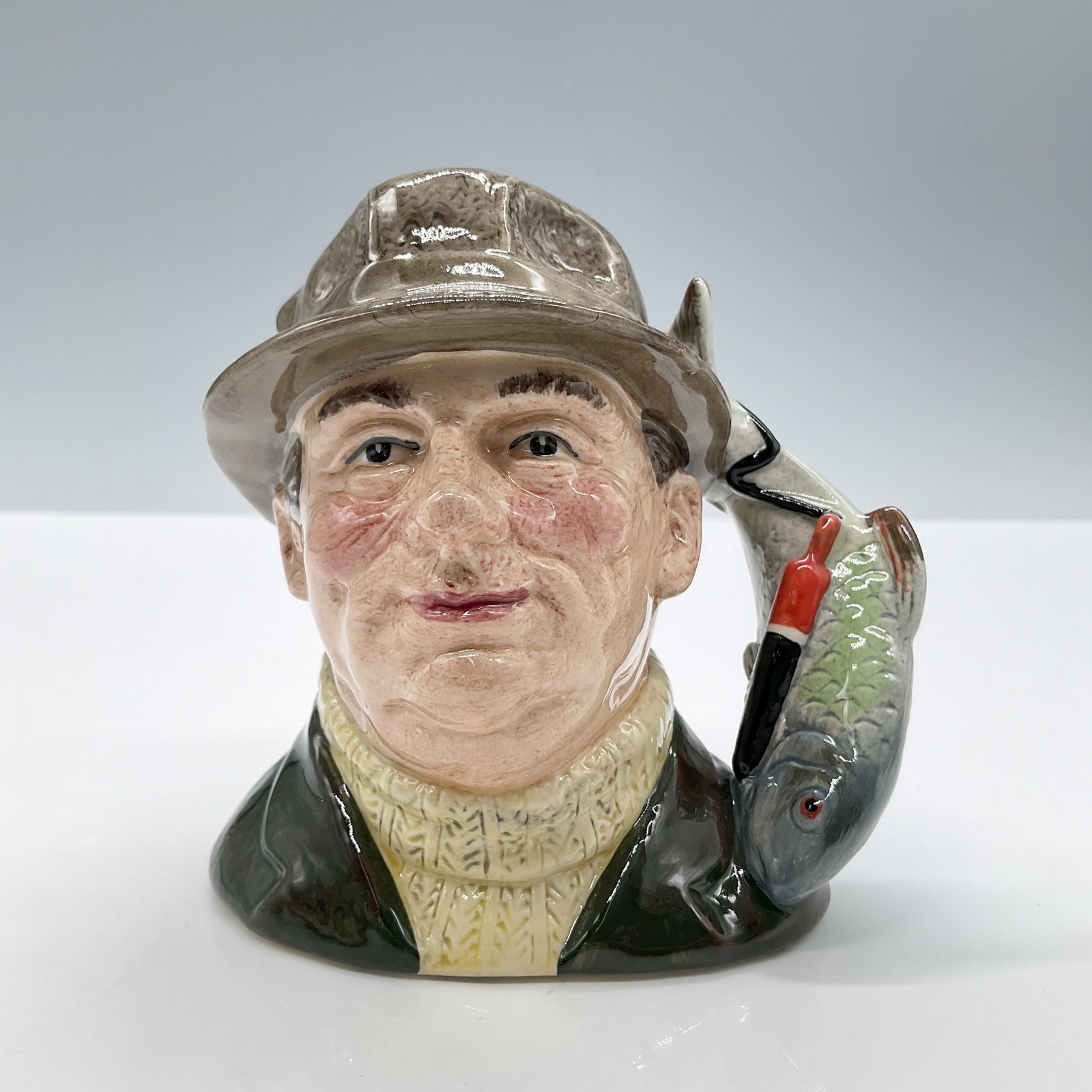 Angler Lure Handle D6866 Small Royal Doulton Character Jug: Style One, fish and lure handle. Green jacket; brown hat; cream pullover. Royal Doulton backstamp. Artist: Stanley J. Taylor Dimensions: 4.75''L x 3.25''W x 4"H Date or Era: 1990 - 1995 Manufacturer o