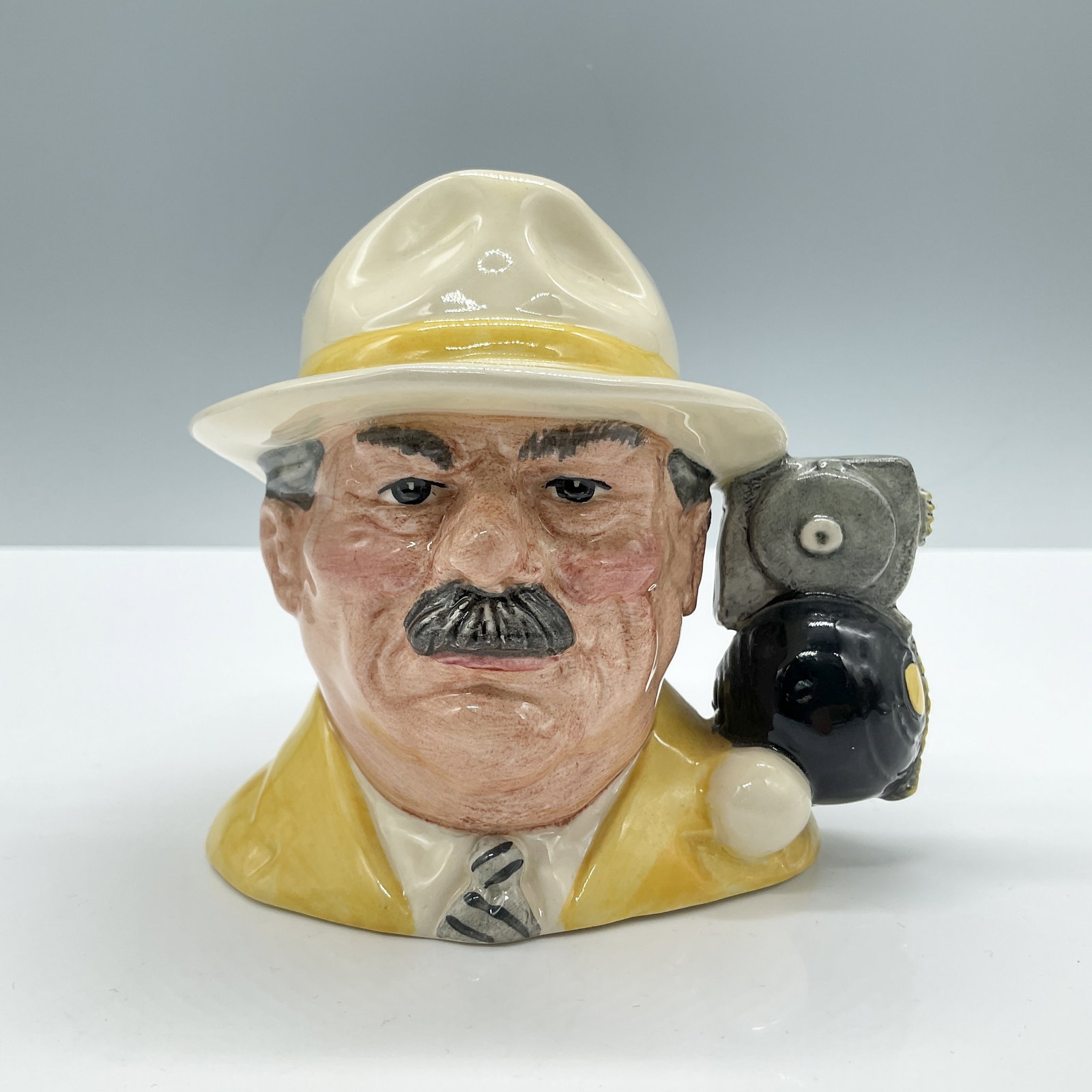 Royal Doulton Small Character Jug, Bowls Player D6896: Features a yellow jacket and white shirt with striped tie, and matching hat. Unmarked. Artist: Stanley J. Taylor Dimensions: 4.25''L x 3.5''W x 4''H Date or Era: 1991- 1995 Manufacturer or Brand: Roya