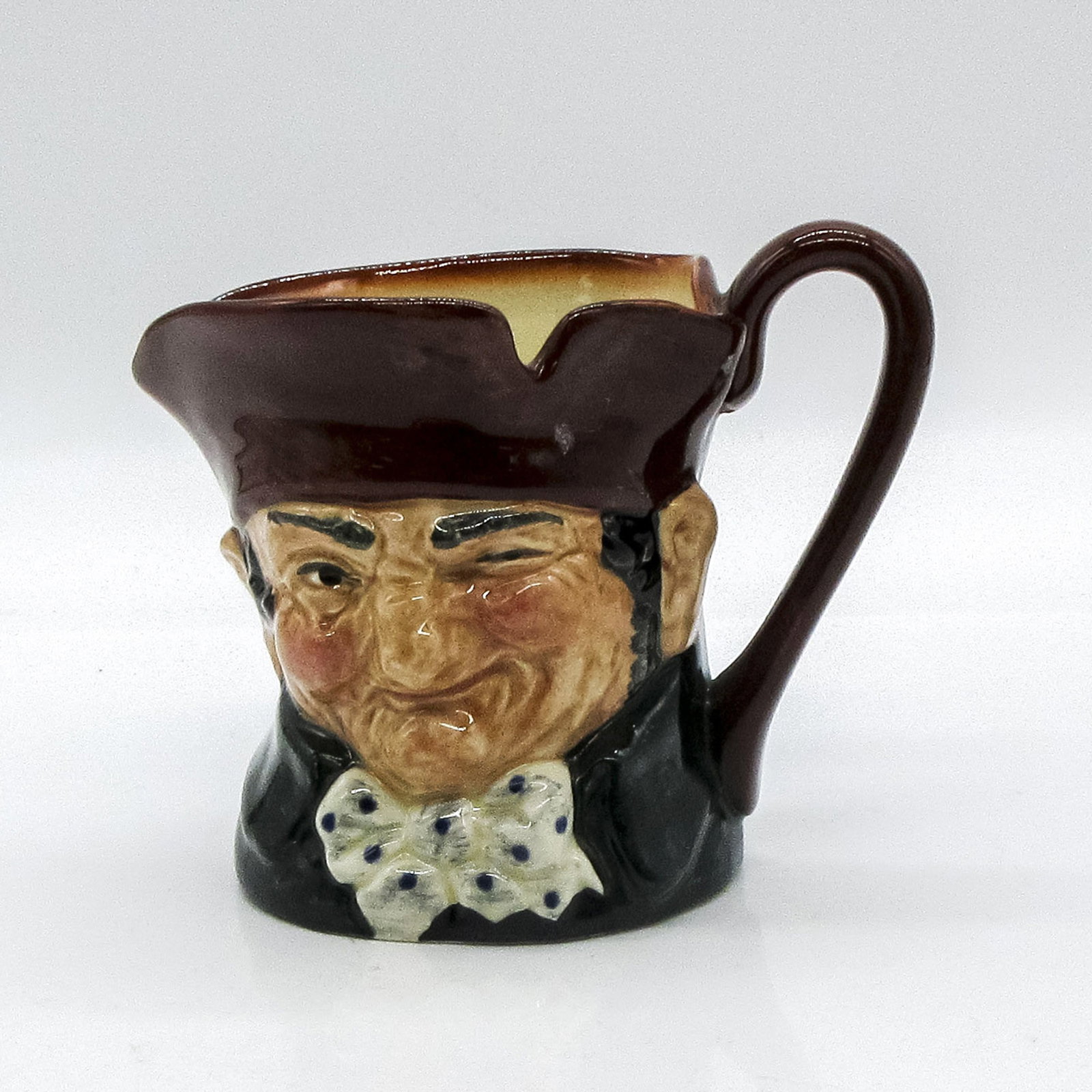 Old Charley D5527 - Small - Royal Doulton Character Jug: Brown hat; dark green coat; blue polka- dot bow tie. "Ten o'clock and all's well" was the familiar call of the Charlies, watchmen who originated during the reign of Charles II and were named after him