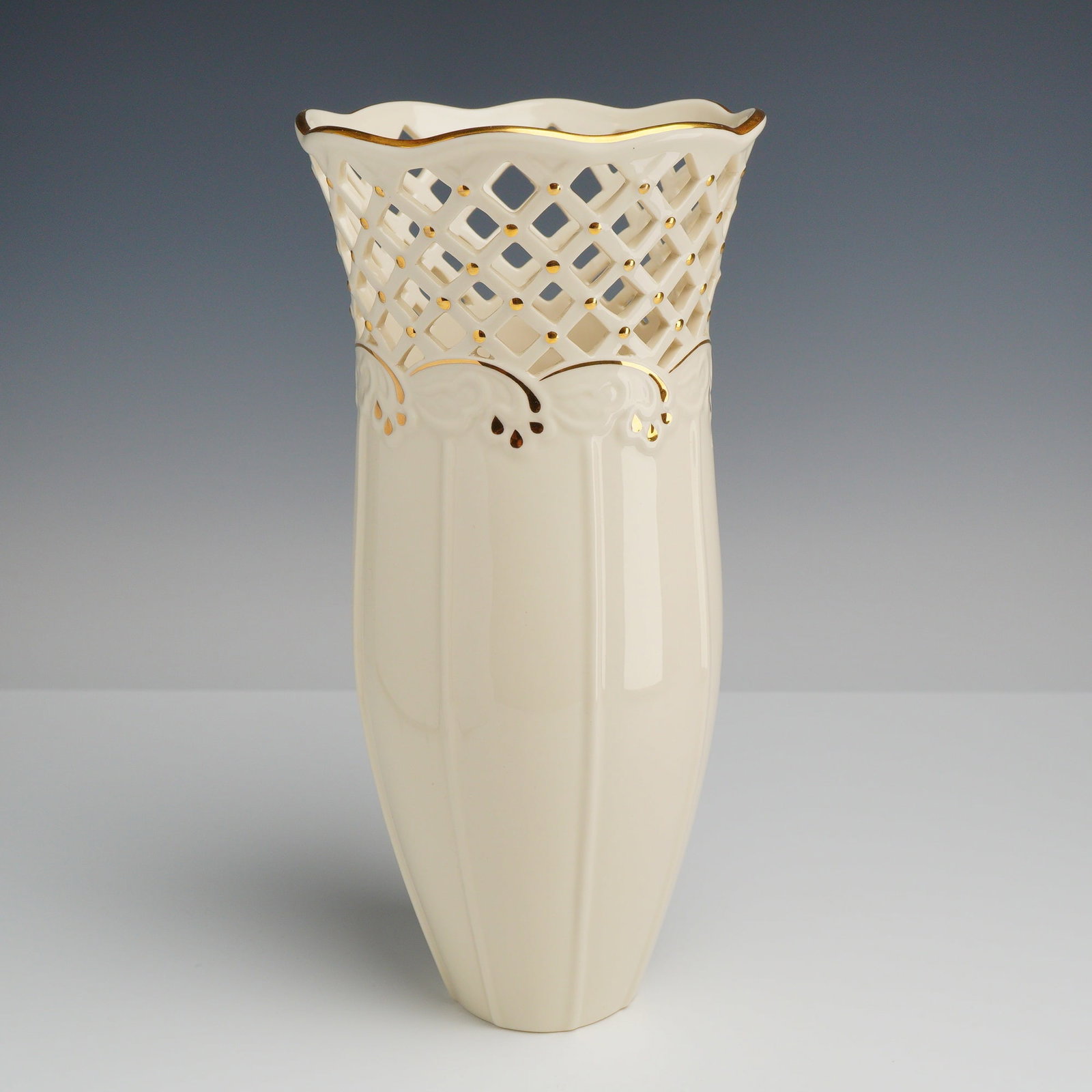 Lenox Porcelain Reticulated Large Vase, Venetian Lace: The vessel features a tall, slender, tapering form with a flared, scalloped rim. The upper section of the body is decorated with an intricate reticulated diamond lattice band. This pierced section is 
