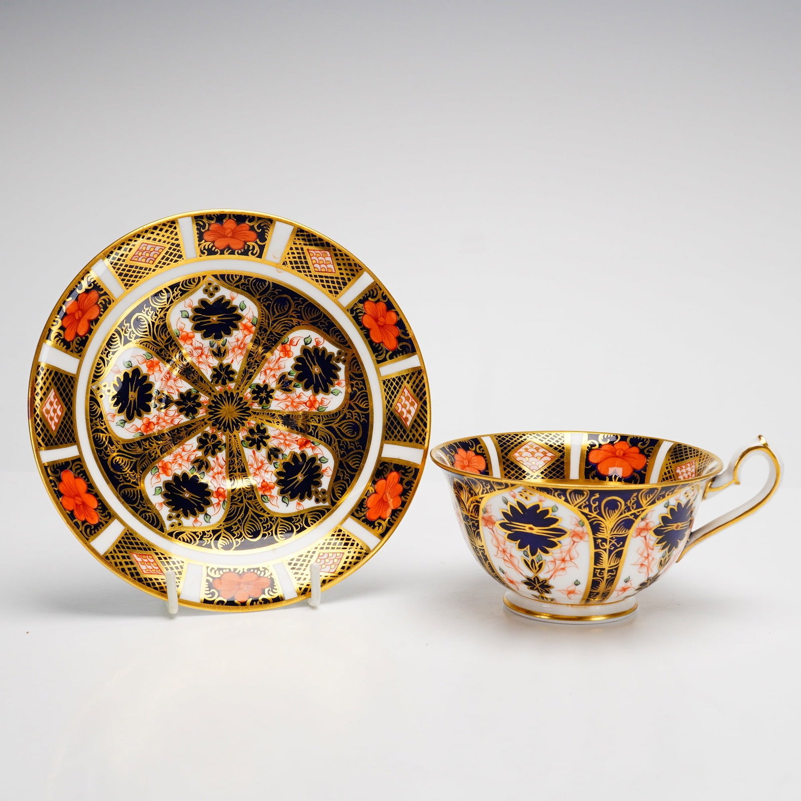 Royal Crown Derby English Bone China Cup and Saucer Set: This two-piece set consists of a footed teacup and matching saucer manufactured by Royal Crown Derby. Crafted from English bone china, both pieces feature the Old Imari pattern, registered as pattern 