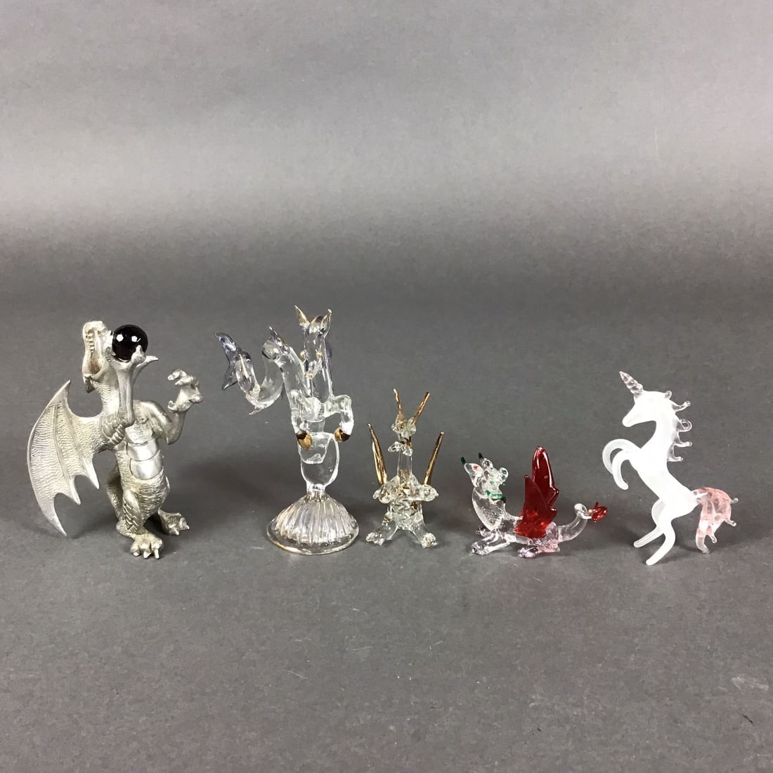 5pc Metal and Glass Dragon and Fantasy Sculptures: This collection of 5pc metal and glass dragon sculptures includes a variety of fantasy-themed figures rendered in cast metal and lampworked glass. The group features a detailed cast metal dragon with 