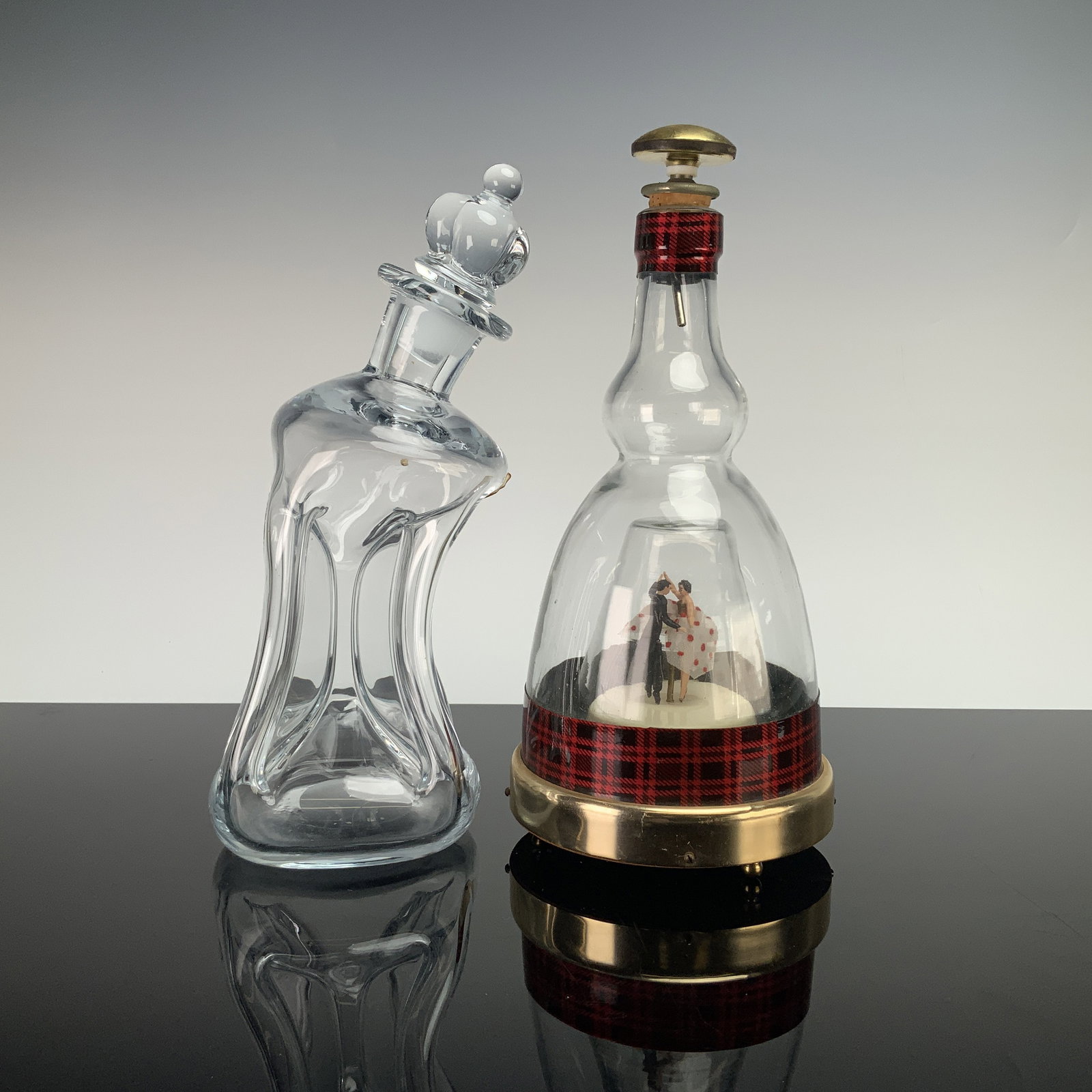 2pc Glass Spirit Decanters, Holmegaard Denmark Kluk Kluk & Plaid Music Box Decanter: This lot consists of two vintage glass spirit decanters. The first is a clear glass Kluk Kluk decanter manufactured by Holmegaard in Denmark. Designed by Jacob E. Bang, the hand-blown vessel features 