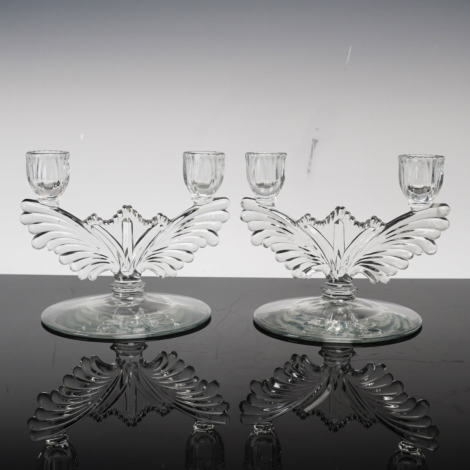 Pair of Heisey Two-Light Glass Candlestick Holders, Phoenix Pattern: This candlestick pair is identified as Heisey pattern number 1428, commonly referred to by collectors as the Phoenix design. Each piece features a stylized wing or plume-shaped central element that br