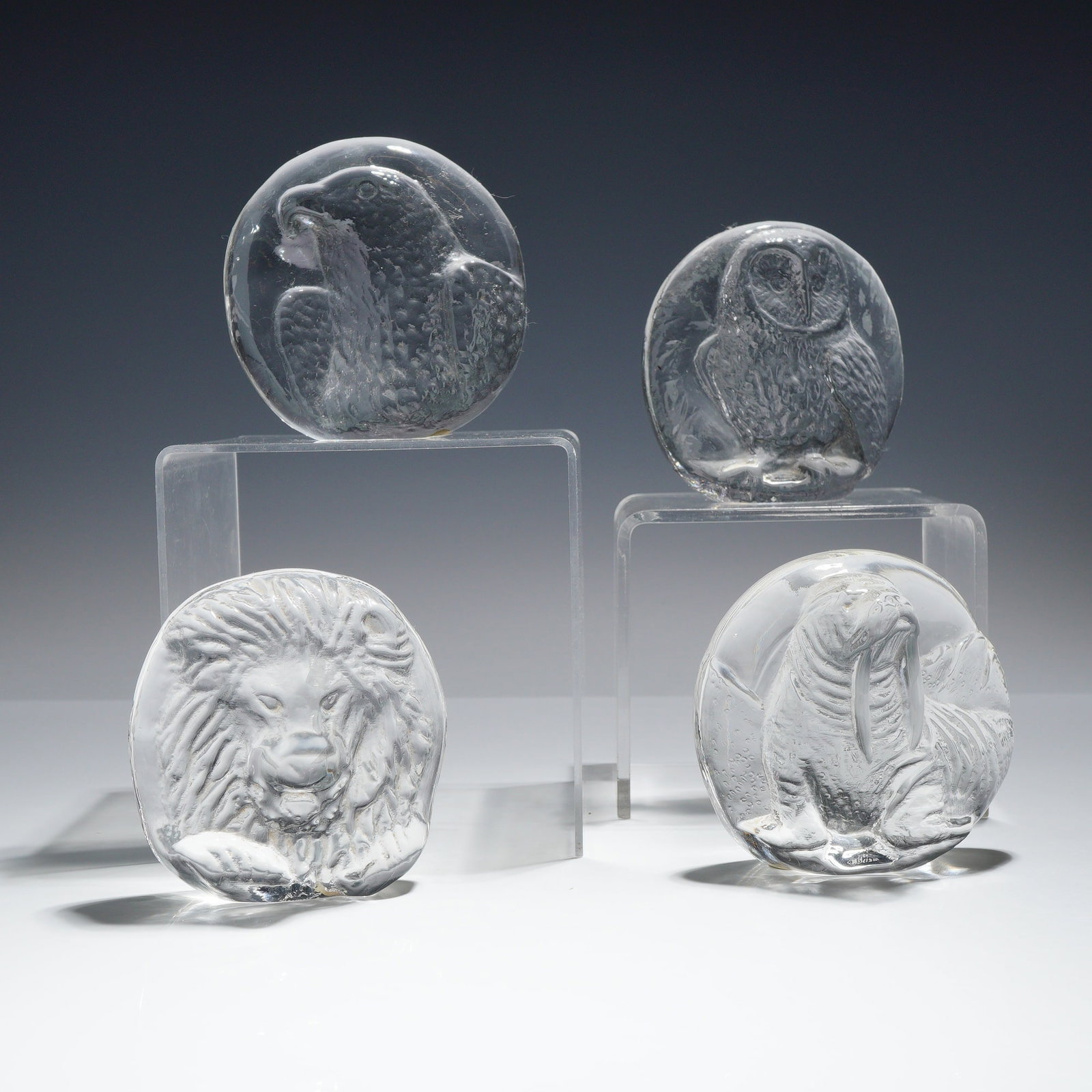 4pc Wedgwood Crystal Animal Paperweights: This collection consists of 4 clear crystal animal paperweights manufactured by Wedgwood in England. Each item is crafted as a heavy, thick molded glass disc with a flattened base. The animals are ren