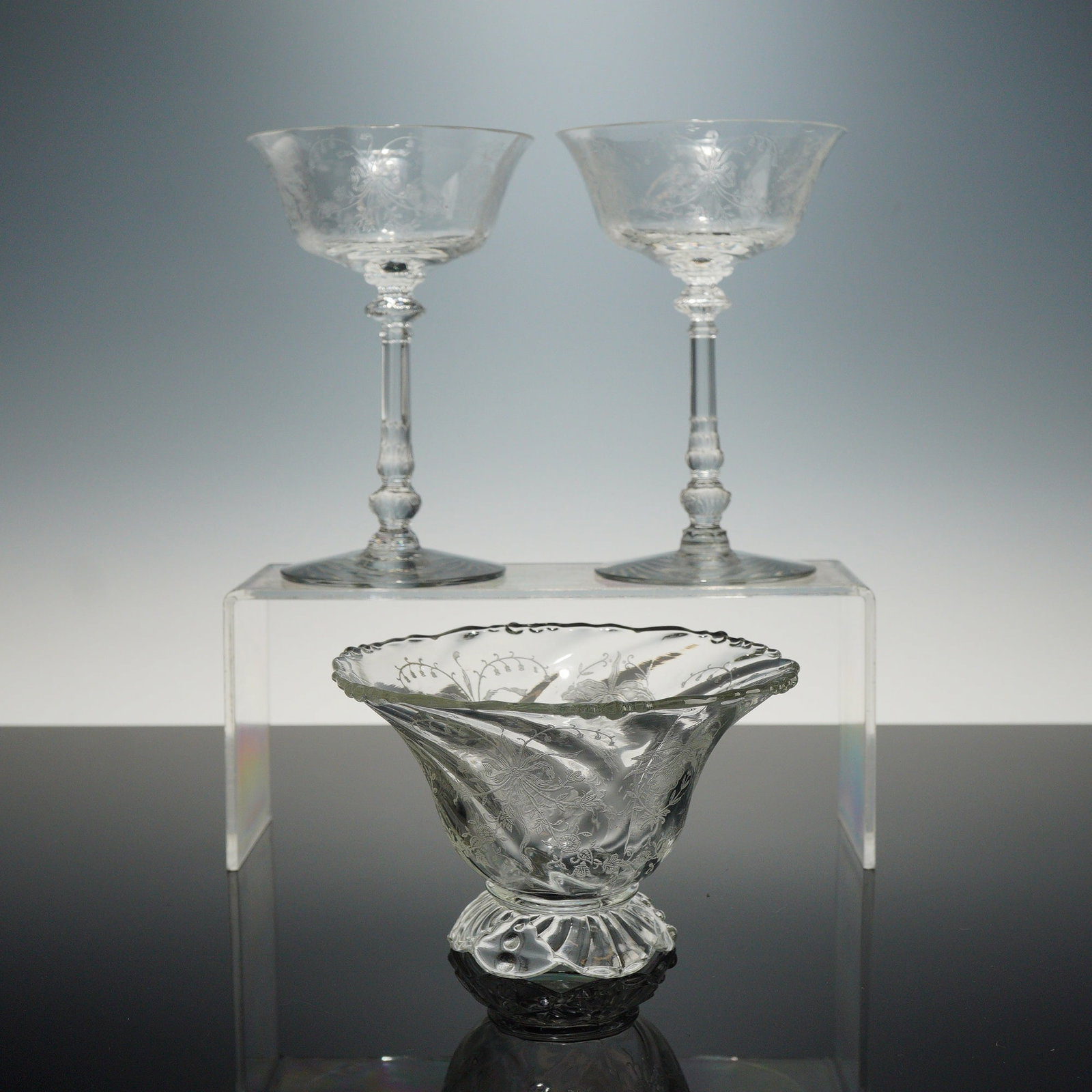 3pc Heisey Orchid Etched Glass Stemware and Footed Bowl: This collection of American elegant glass features the Orchid pattern by Heisey. The set includes two champagne or tall sherbet stems and one footed bowl. Each piece is decorated with a fine needle-et
