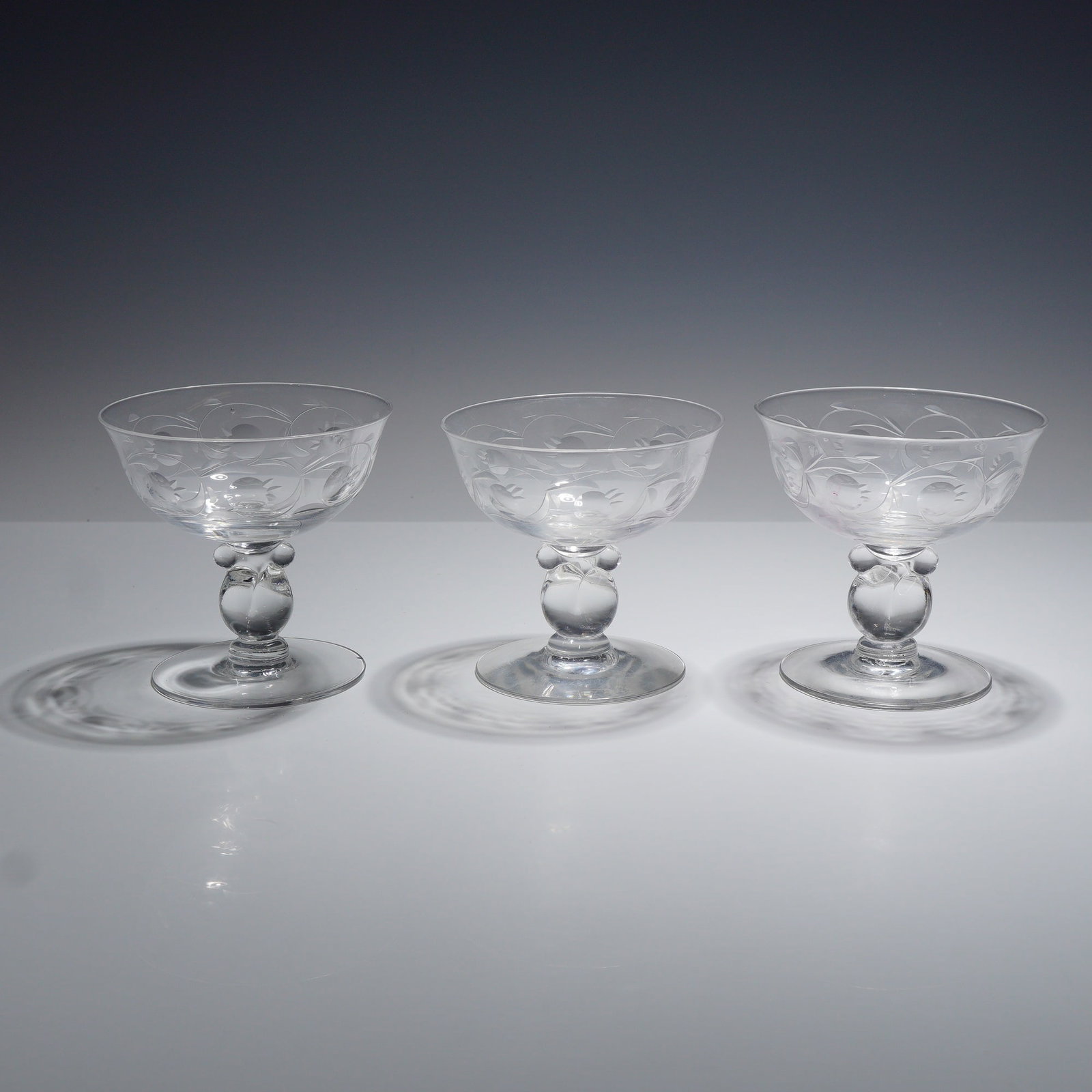 Three Heisey Moonglo Etched Lariat Pattern Crystal Champagne Glasses: This set of three glasses is identified as Heisey crystal in the Lariat stem pattern featuring the Moonglo wheel-etched decoration. The items are clear lead crystal stemmed glasses intended for use as