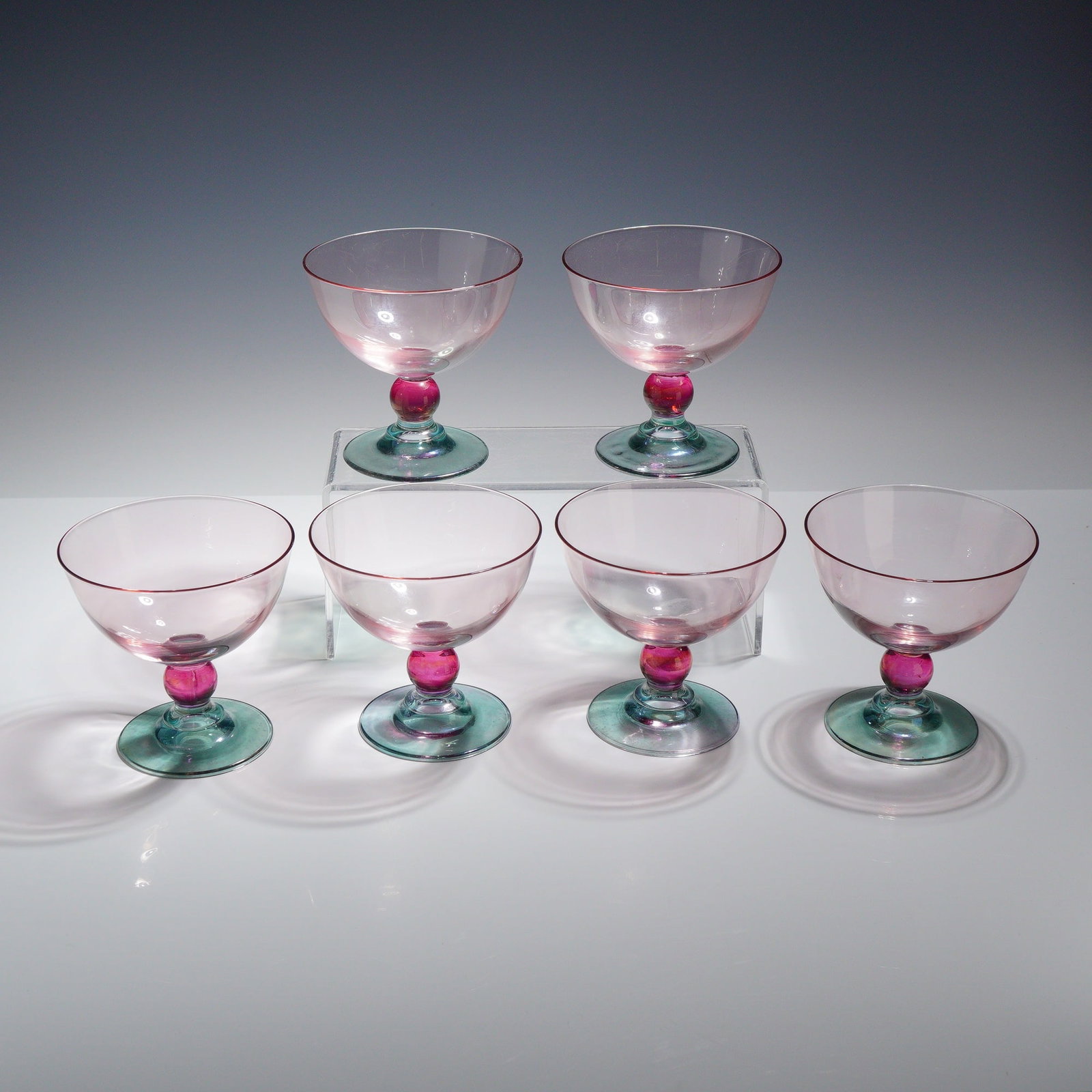 6pc Mila International Rainbow Pink Green Champagne Coupes: This collection is constructed from hand-blown glass in three distinct colors. Each vessel features a wide, shallow, transparent pale rose-pink bowl. The stem is detailed with a vibrant, fuchsia-color