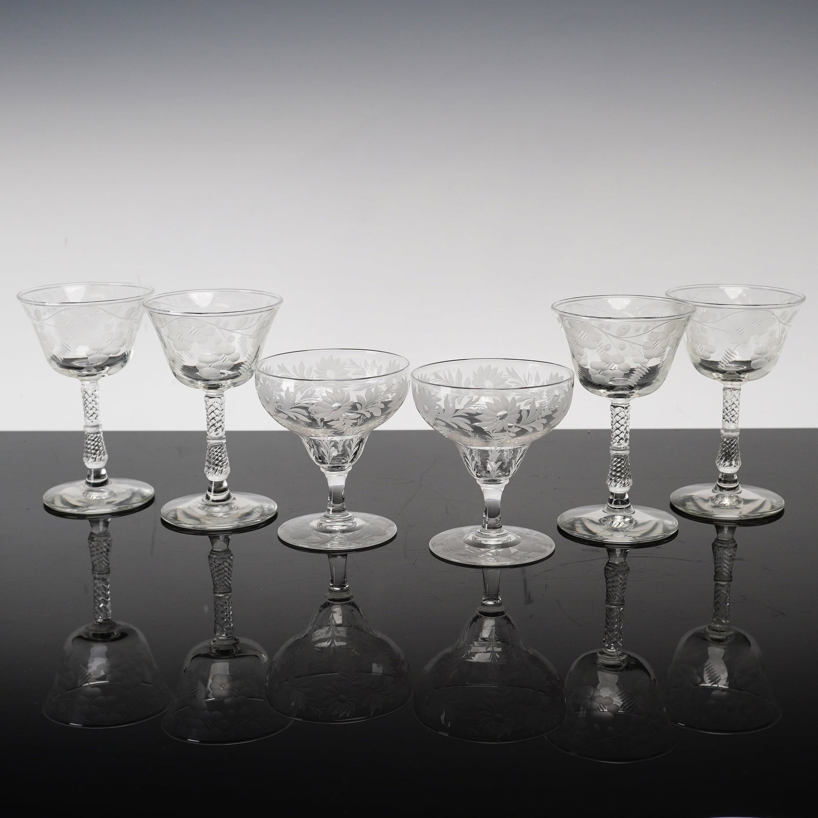 Set of Six Libbey Rock Sharpe Etched and Cut Crystal Stemware Glasses: This sharpe glass mixed lot consists of six lead crystal stems attributed to Libbey Rock Sharpe, featuring two distinct patterns. The first group includes four tall stems with flared bowls decorated w