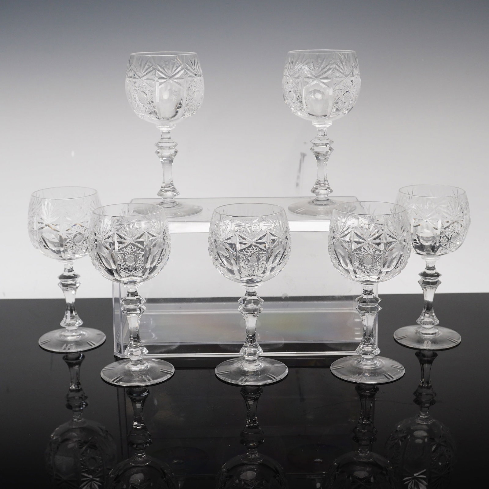 Set of 7 Cut Crystal Wine Glasses in the Mill Pattern: A set of 7 lead crystal wine glasses featuring a traditional hand-cut design. Each glass displays a rounded bowl decorated with central hobstar motifs, vertical fan cuts, and a lower register of diamo