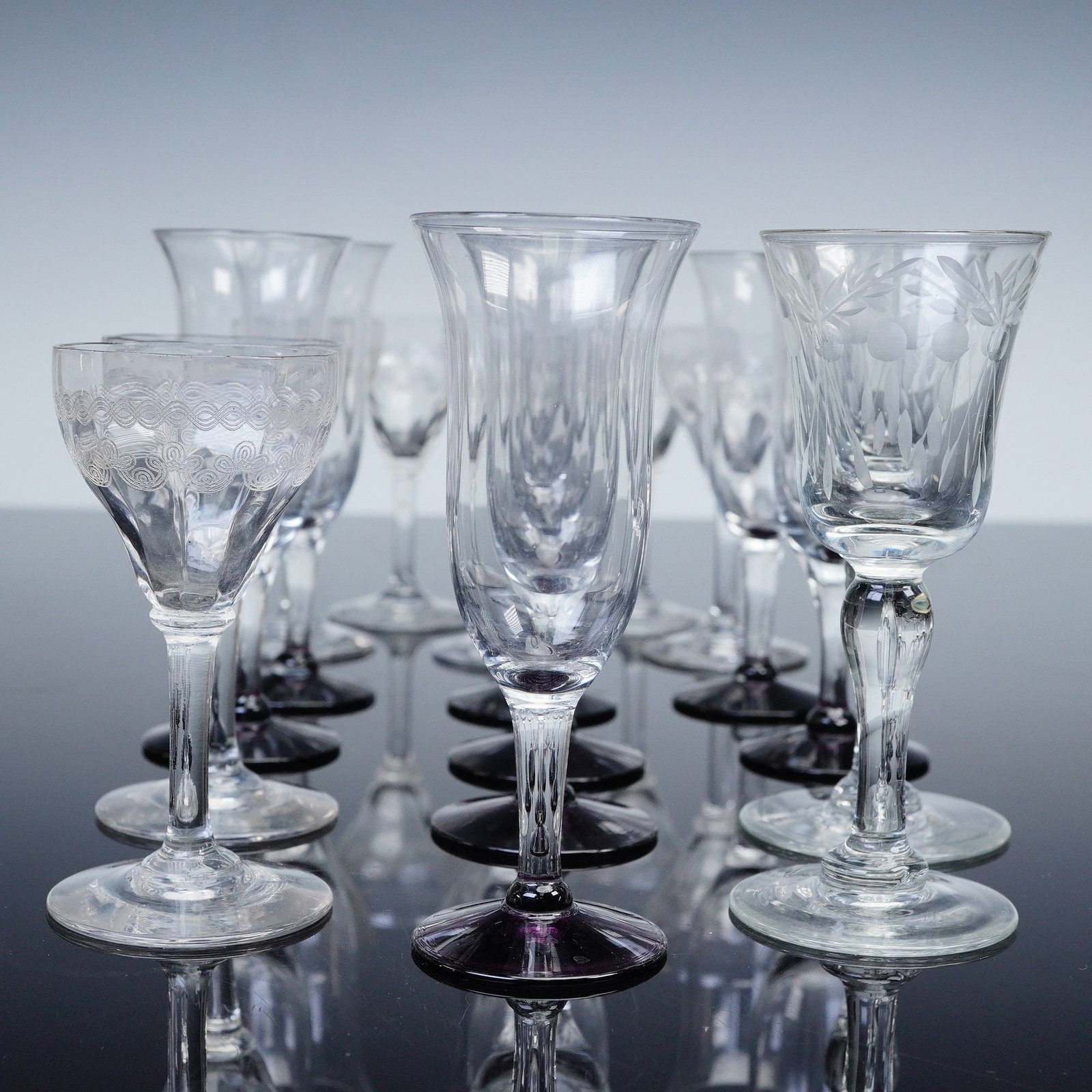 17pc Etched and Cut Cordial Stemware Glasses: A diverse assemblage of seventeen vintage pieces of stemware comprising an assortment of etched and cut glass goblets and wine glasses in varying forms and motifs. Includes eight short stemmed glasses