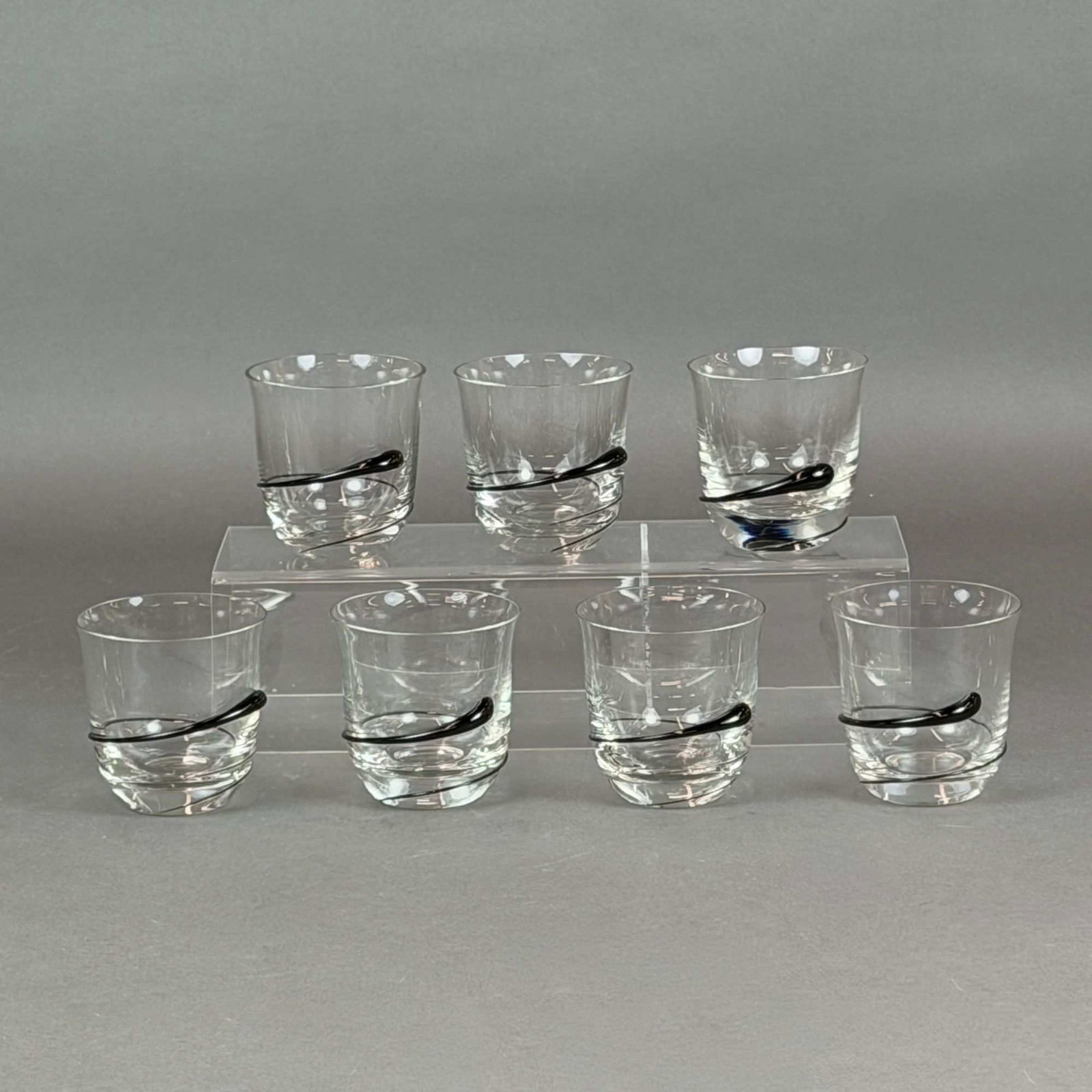 7pc Rosenthal Studio-Line Black Swirl Accent Whiskey Glasses: This set of seven clear glass whiskey tumblers is from the Rosenthal Studio-Line. Each glass is hand-blown and features a distinctive decorative element consisting of a single, thick black glass trail