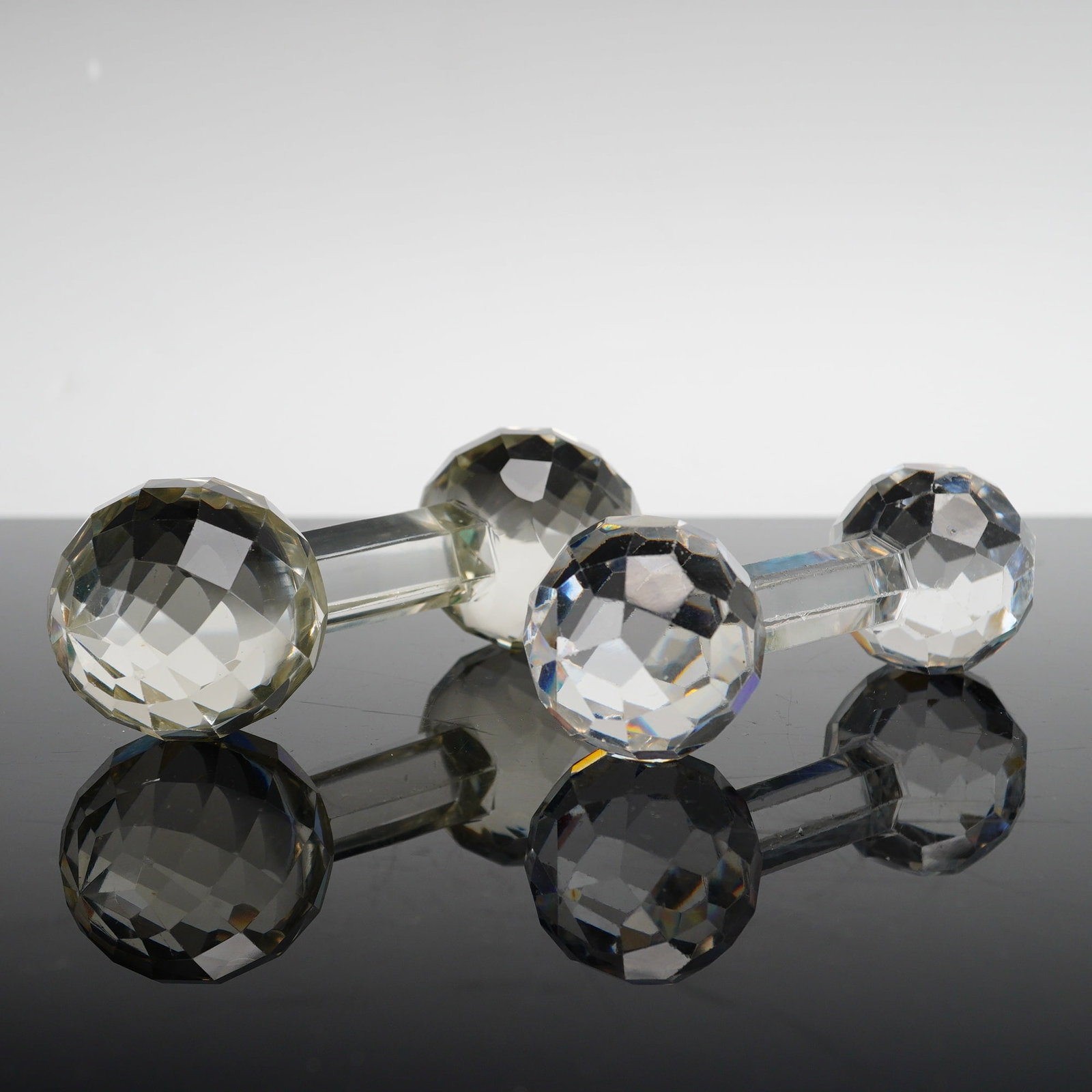 A Pair of Cut Crystal Knife Rests, American Brilliant Style: This lot features a pair of cut crystal faceted knife rests. These items are designed in the American Brilliant style, characterized by a barbell form with multi-faceted spherical ends and a smooth, c