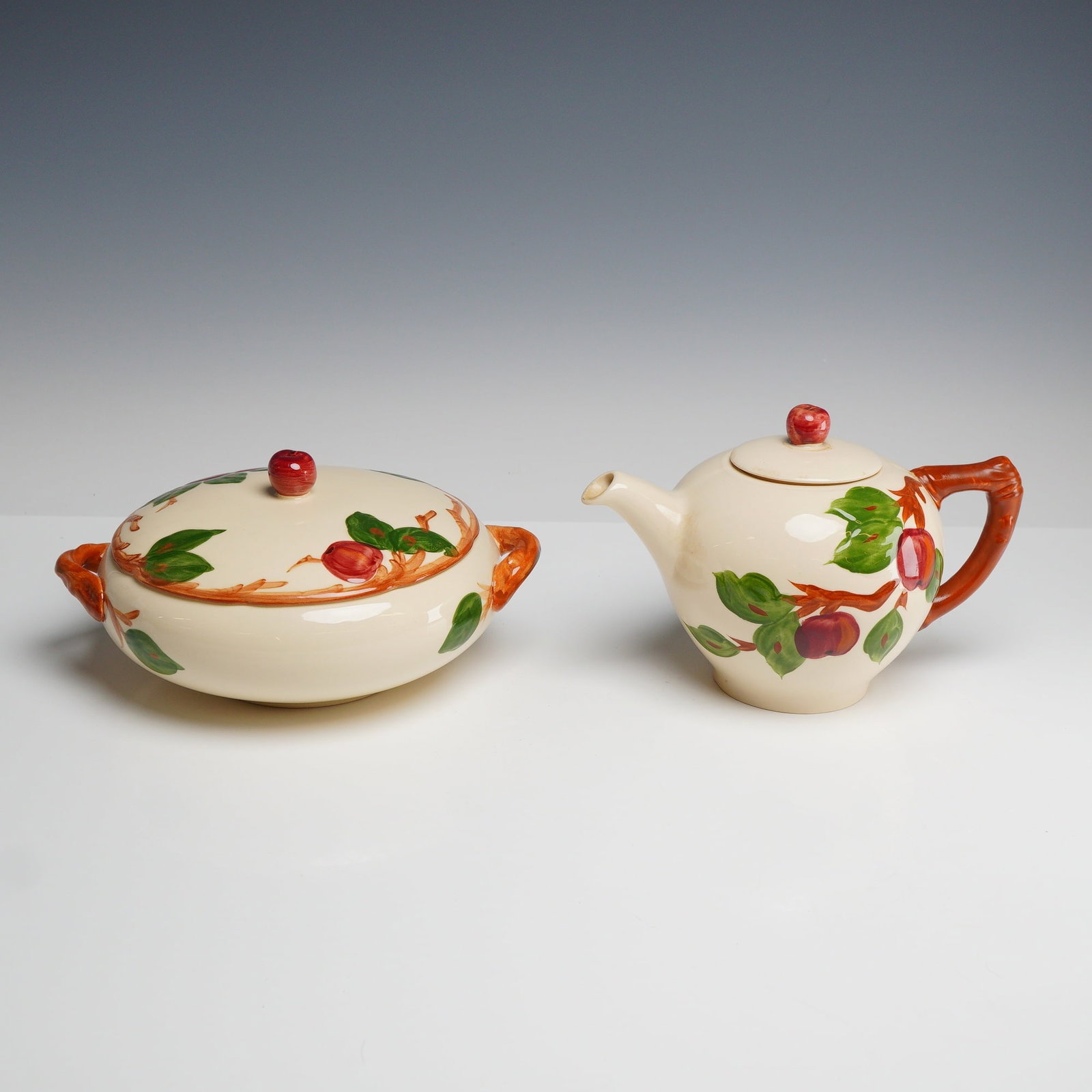 2pc Franciscan Apple Pattern Ceramic Teapot and Serving Dish: This lot consists of two pieces of Franciscan dinnerware in the Apple pattern, including a teapot and a covered serving dish. Each piece is constructed from glazed earthenware and features hand-decora